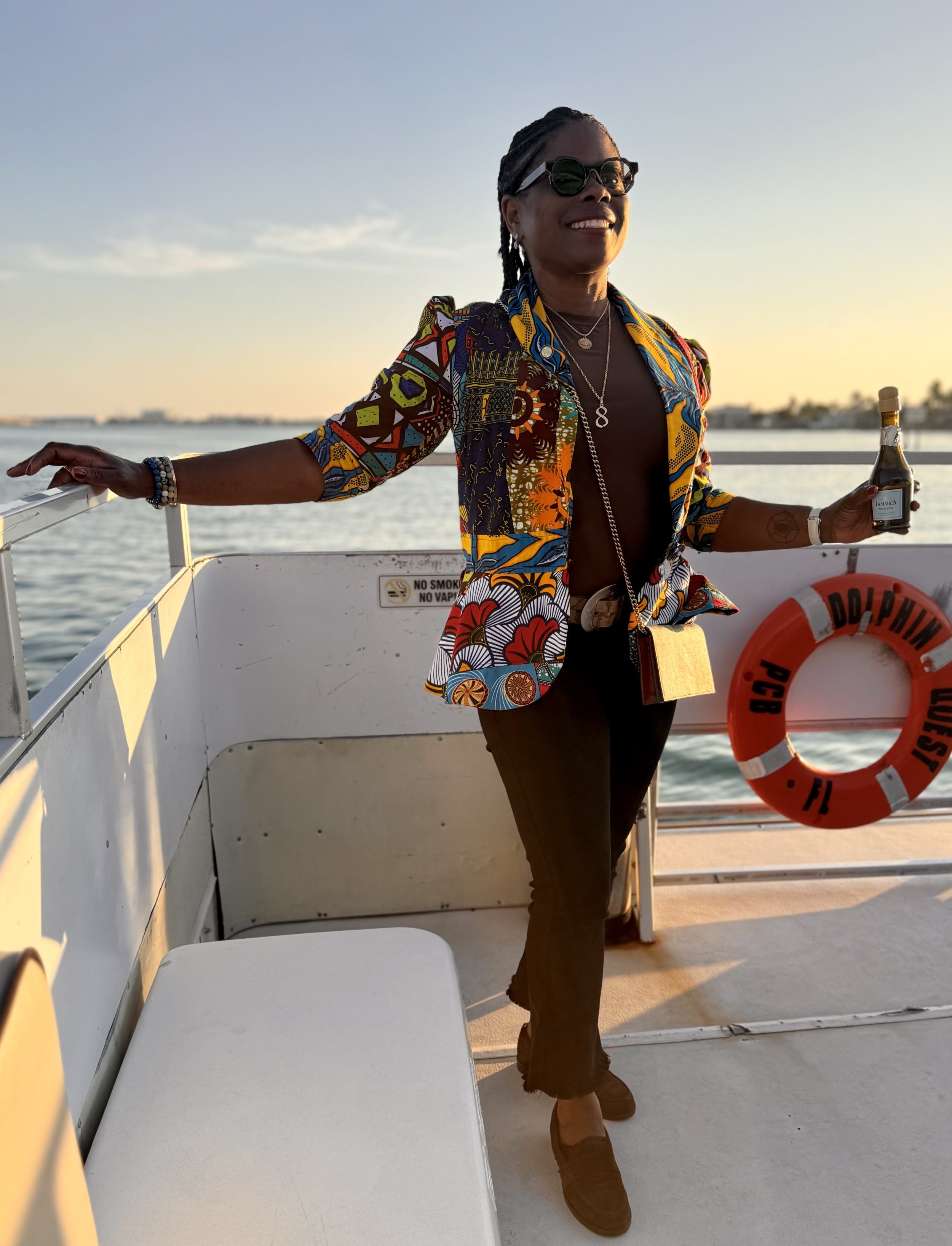 Meg Charles enjoying a sunset boat moment representing success, freedom, and aligned living