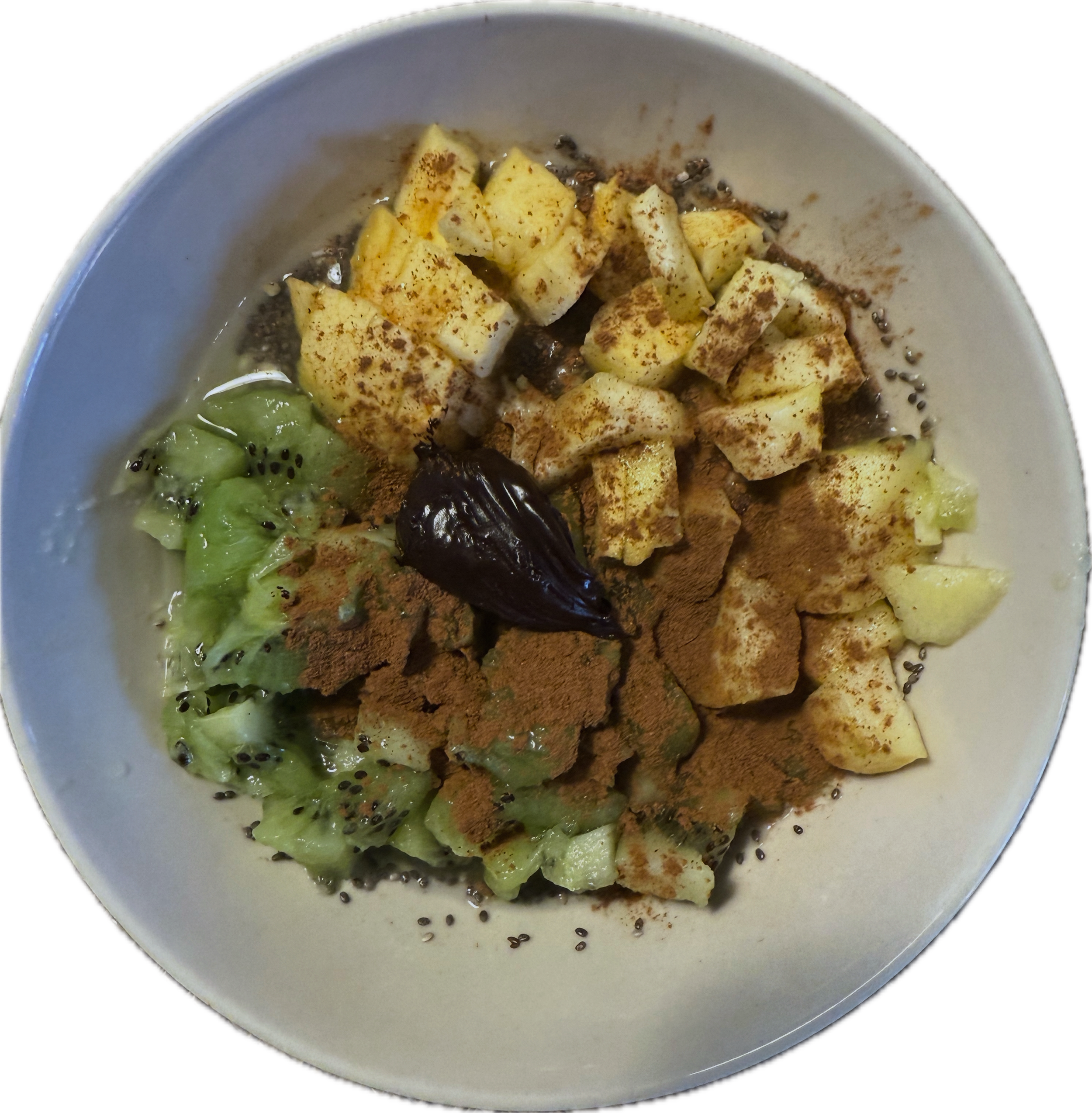 Bol de smoothie avec morceaux de kiwi, pommes, canelle en poudre, graines de chia et pate à tartiner.