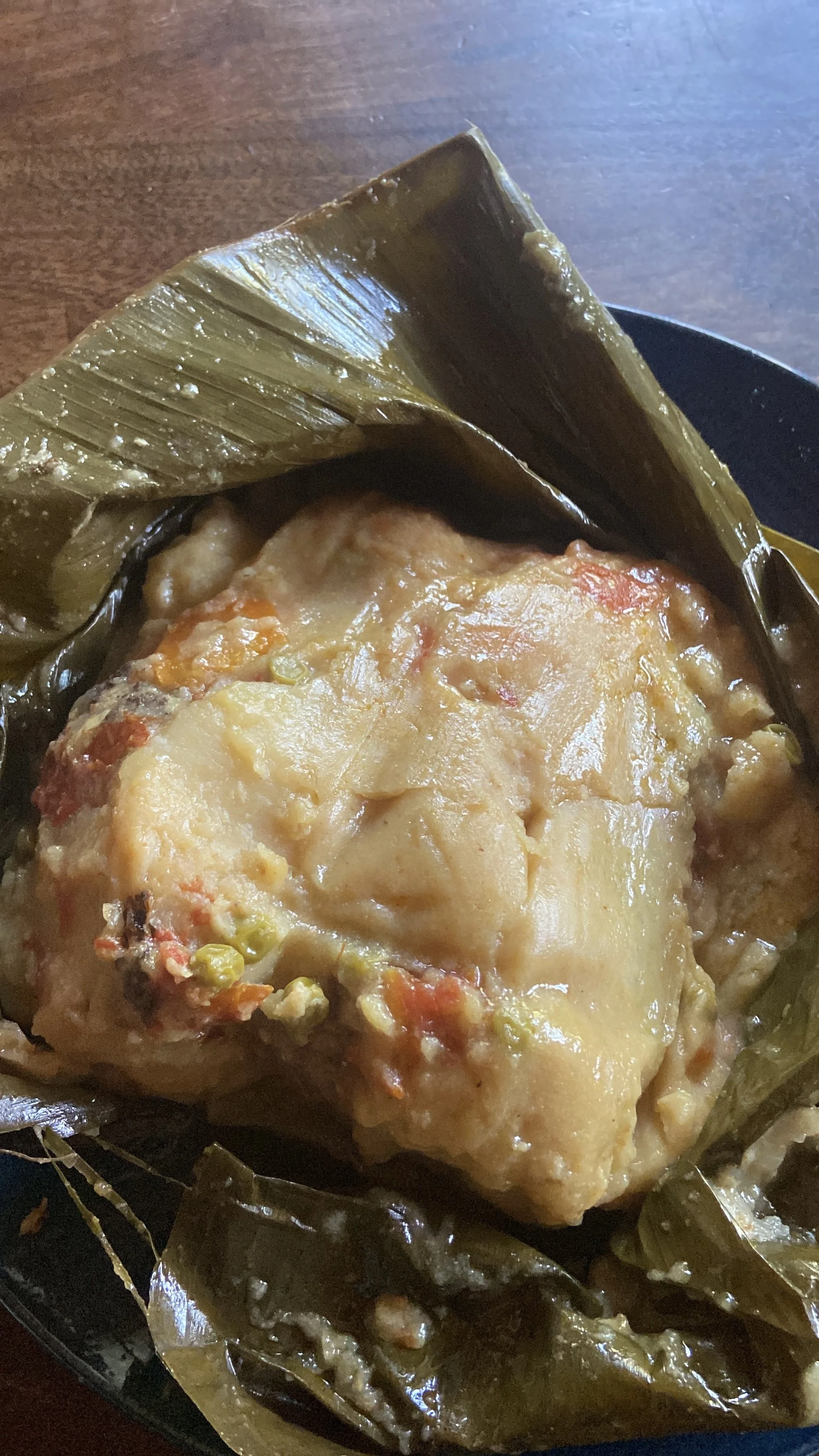 A serving of chicken pot pie topped with melted cheese and surrounded by banana leaves.