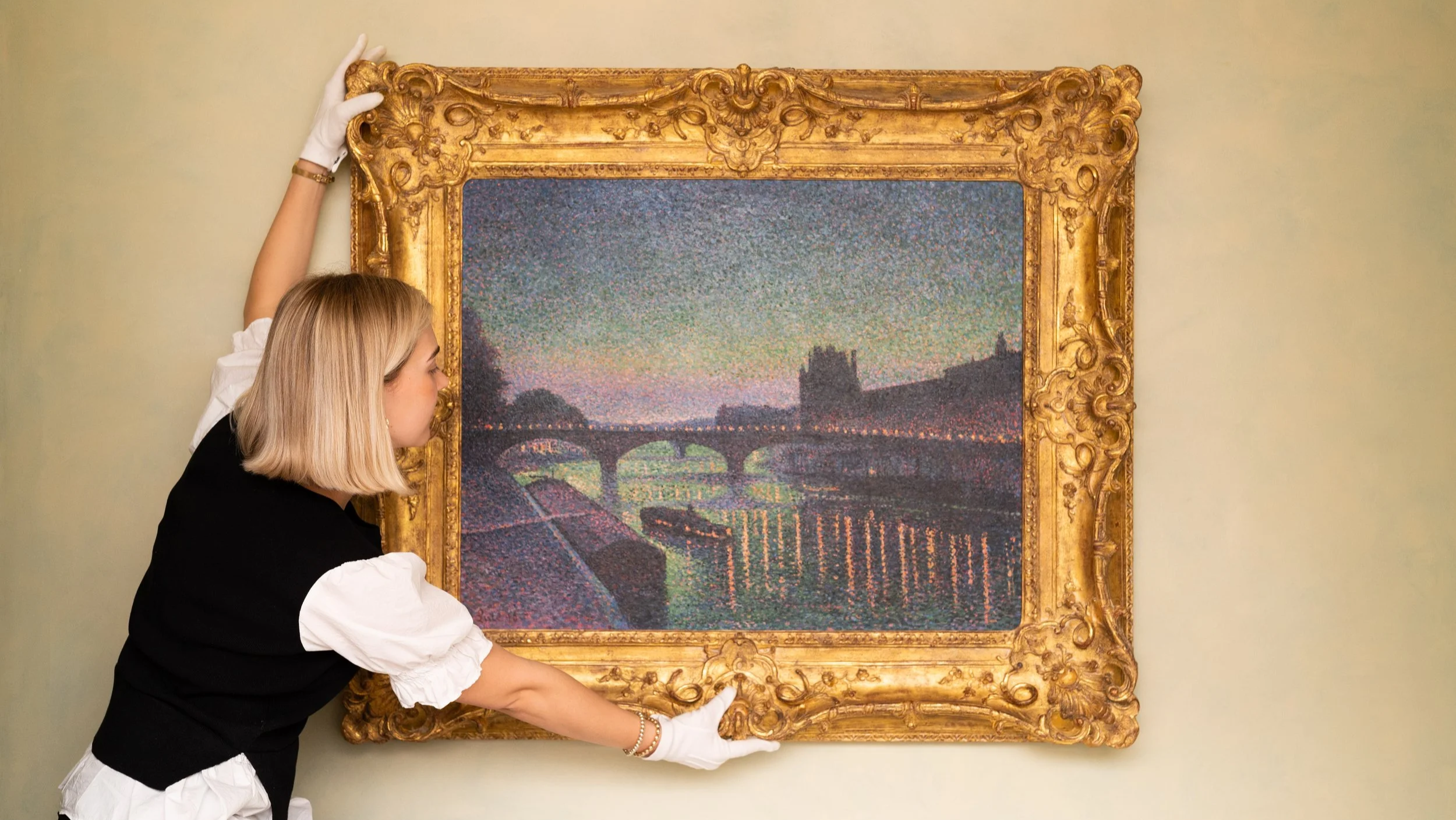 Museum curator handles a landscape painting with a gilded frame