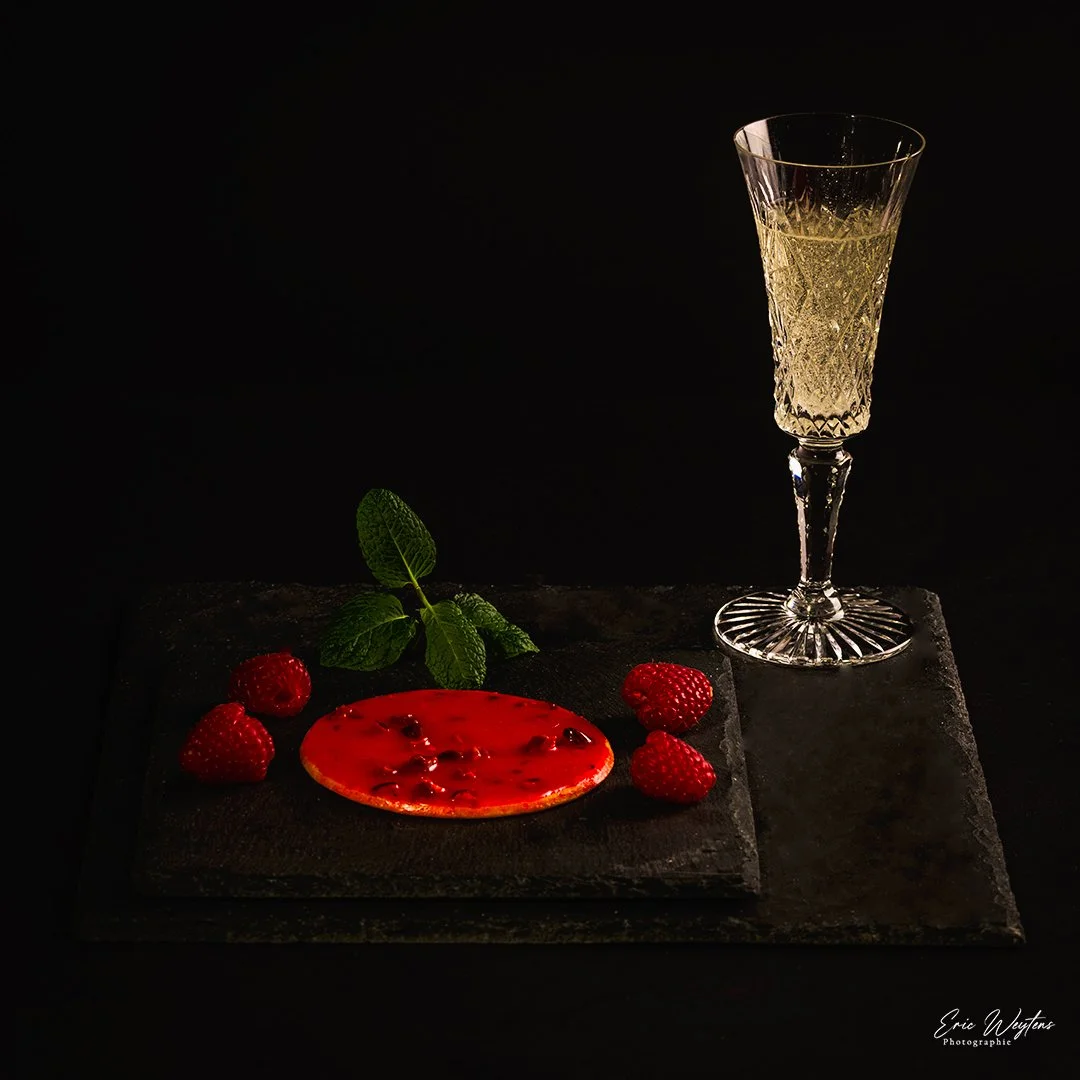 Verre à champagne, radis, menthe et plaque de chocolat sur une surface noire.