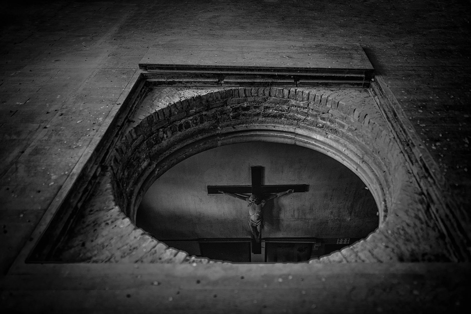 Vue en plongée d'une niche en pierre avec une peinture de Jésus crucifié vue par le haut.