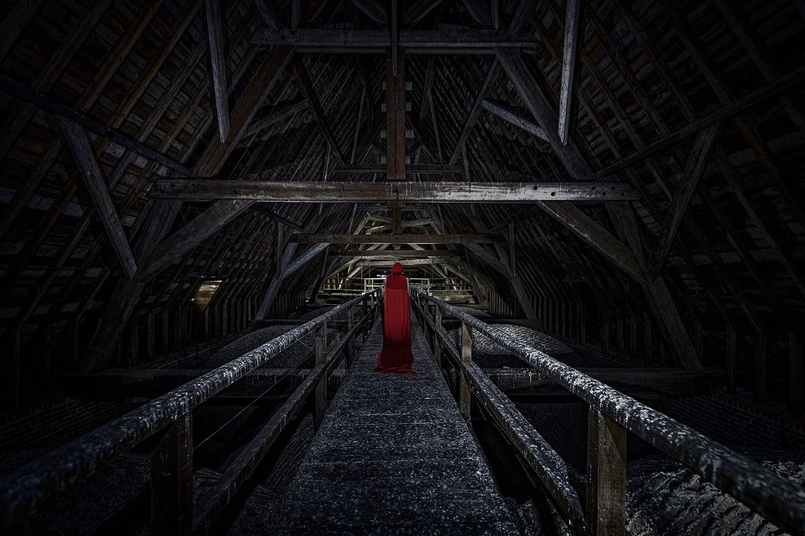 Une personne en cape rouge marche dans une grande structure en bois sombre avec un plafond en forme de voûte.