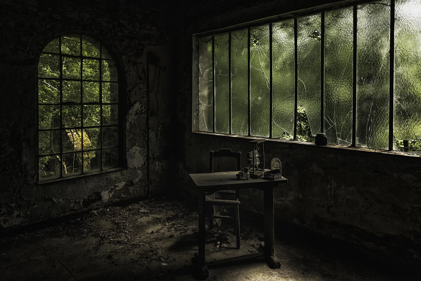 Une pièce abandonnée avec des fenêtres brisées, un mur en pierre, une table en bois et des insectes, laissant entrer la lumière naturelle.