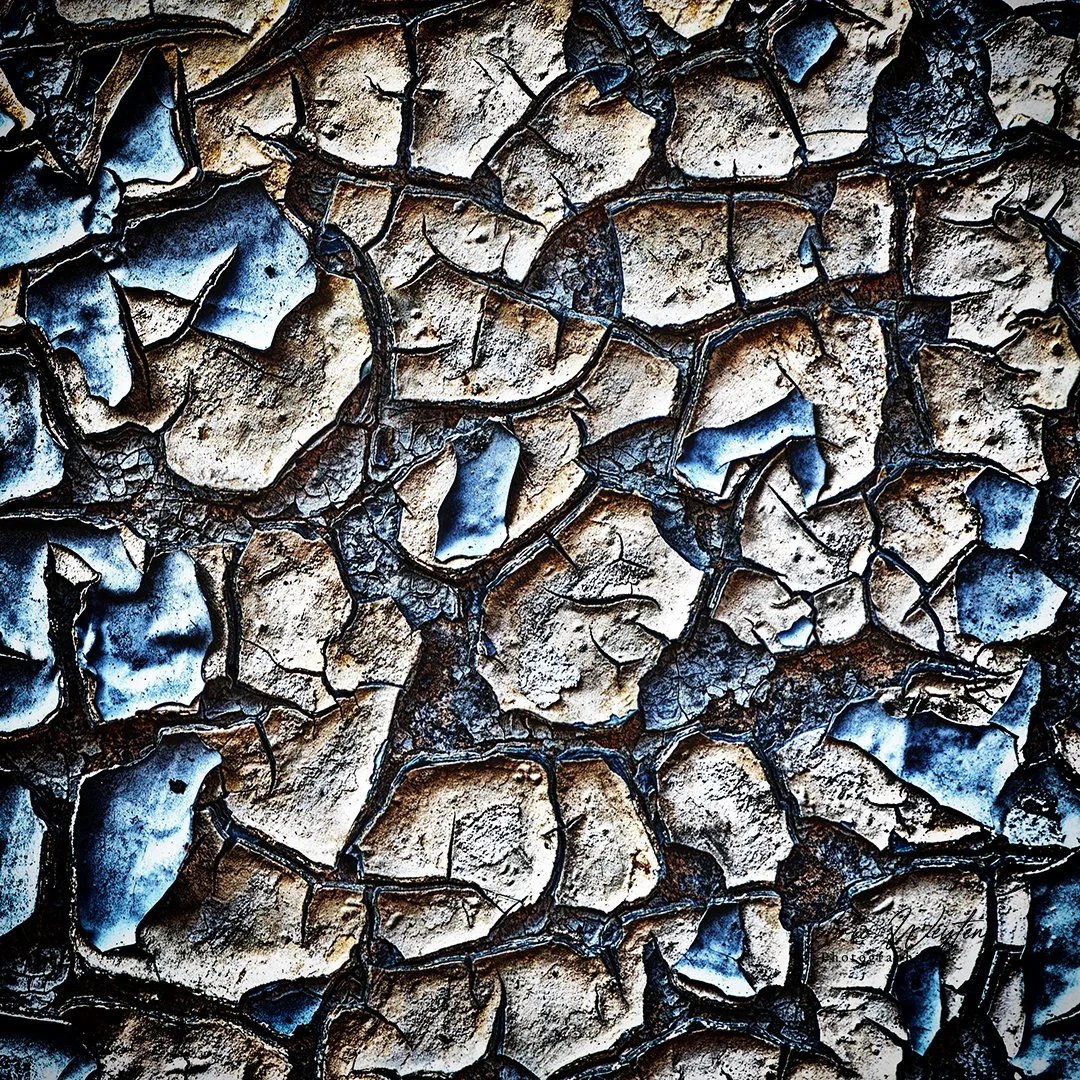 Texture de terre craquelée avec des couleurs marron, beige et des nuances de bleu et noir.