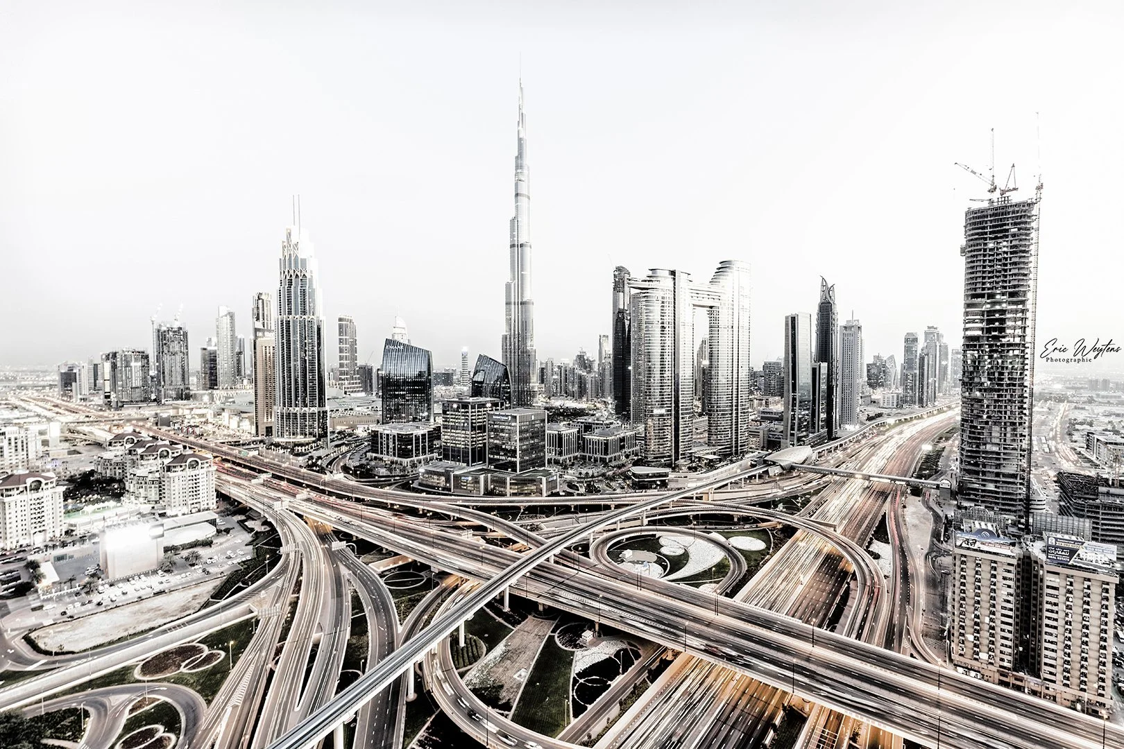 Vue aérienne d'une skyline urbaine avec de nombreux gratte-ciel et un réseau d'autoroutes enchevêtrées.