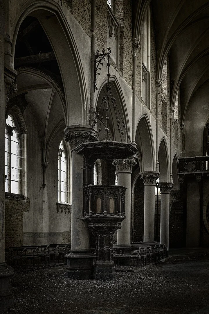 Intérieur d'une ancienne église gothique avec des colonnes en pierre, des vitraux et un chœur en bois sombre.
