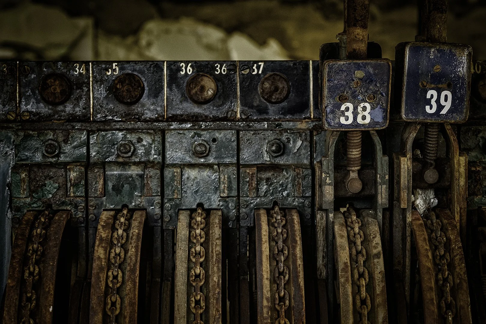 Une machine ancienne avec des engrenages et des chaînes rouillées, numérotée avec les chiffres 34, 35, 36, 37, 38 et 39.