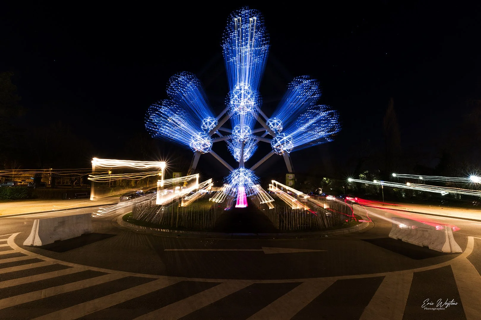 Roue d'adrénaline illuminée avec des lumières bleues et blanches, prise en longue exposition la nuit, utilisée dans un festival ou une fête foraine.