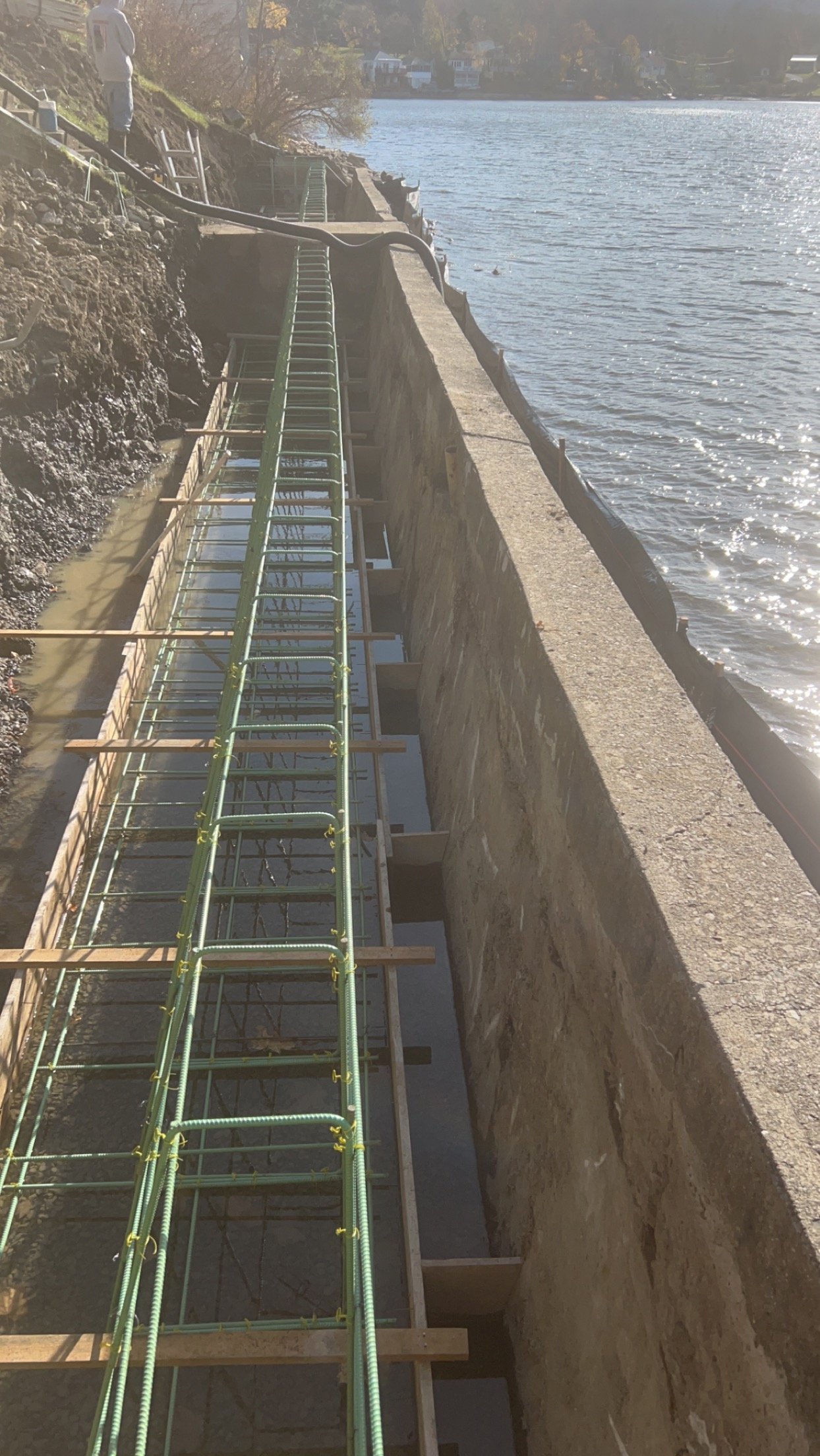 Construction site along a water body with scaffolding and wooden supports, possibly for building or repairing a waterfront structure.