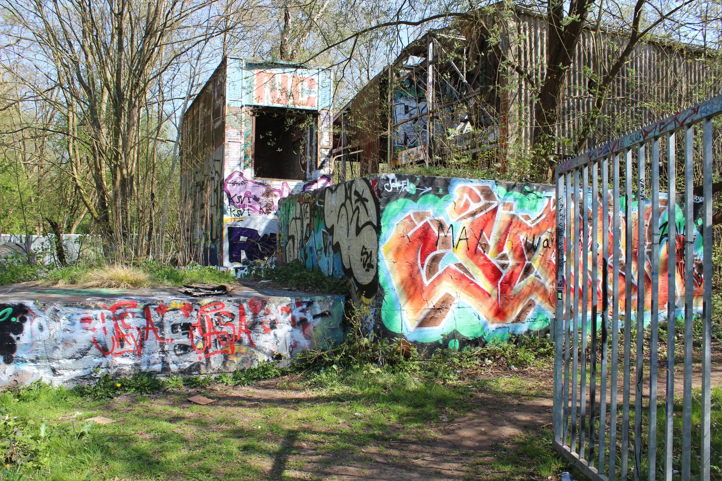 Verfallenes Gebäude mit Graffiti an Wänden in einer Grünen Umgebung.