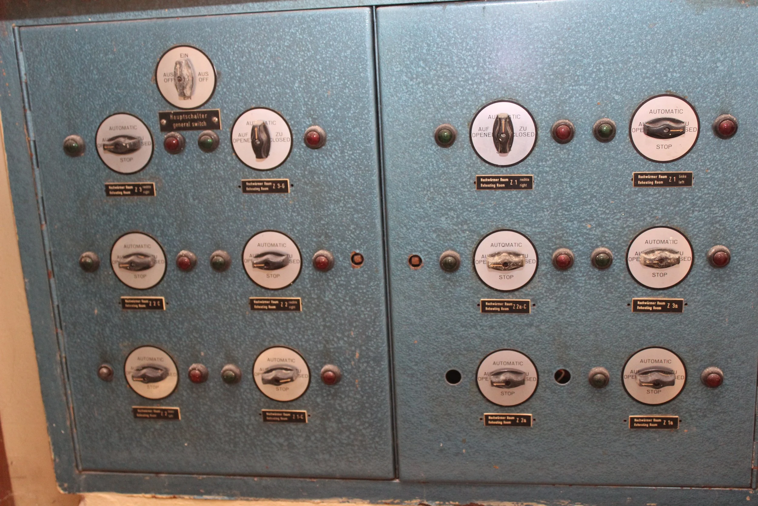 Ein Steuerpult mit mehreren Schaltern und Kontrollleuchten, vermutlich für die Steuerung von Heizungen oder technischen Anlagen in einem Gebäude.