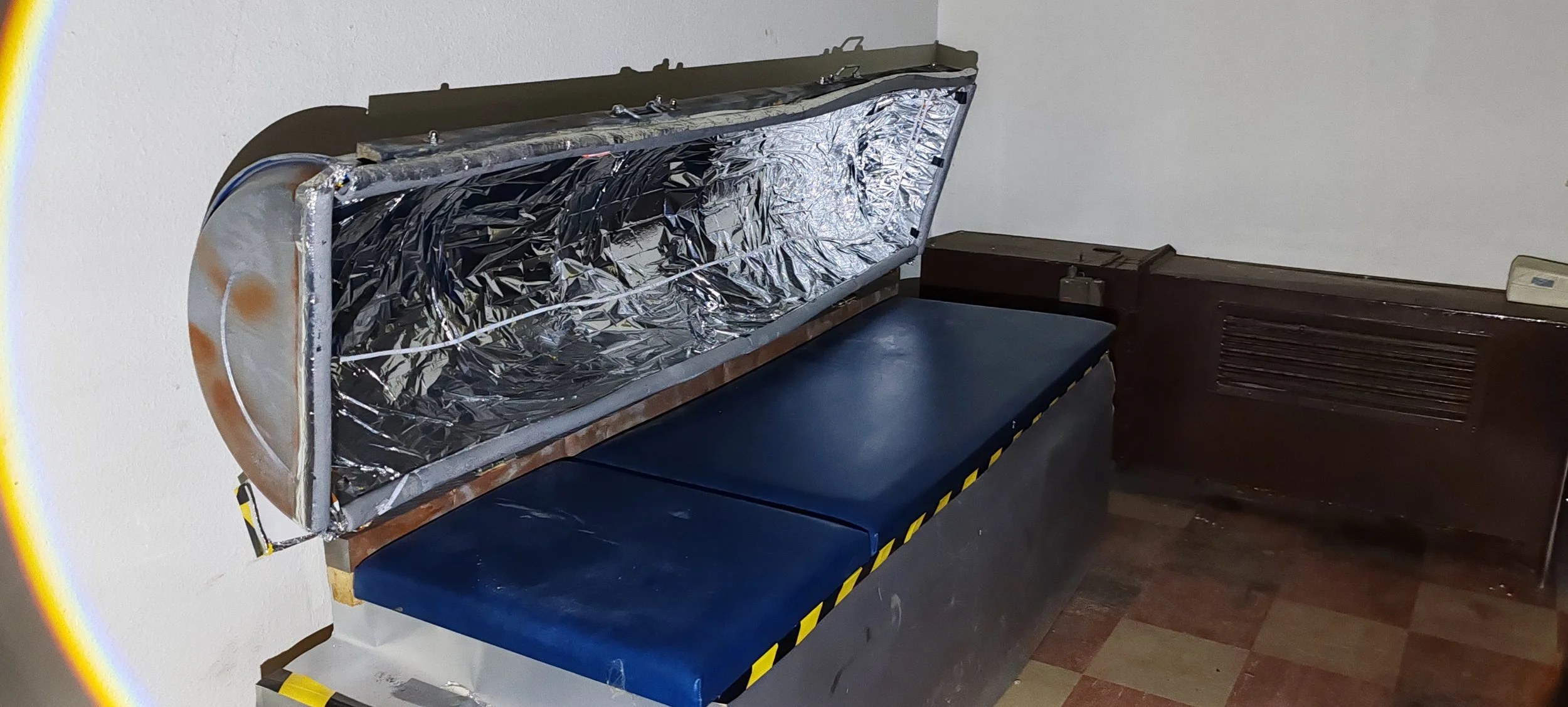 Boden mit einer Decke und Zubehör, hinten ein Heizgerät, eine Wand und eine Sitzbank