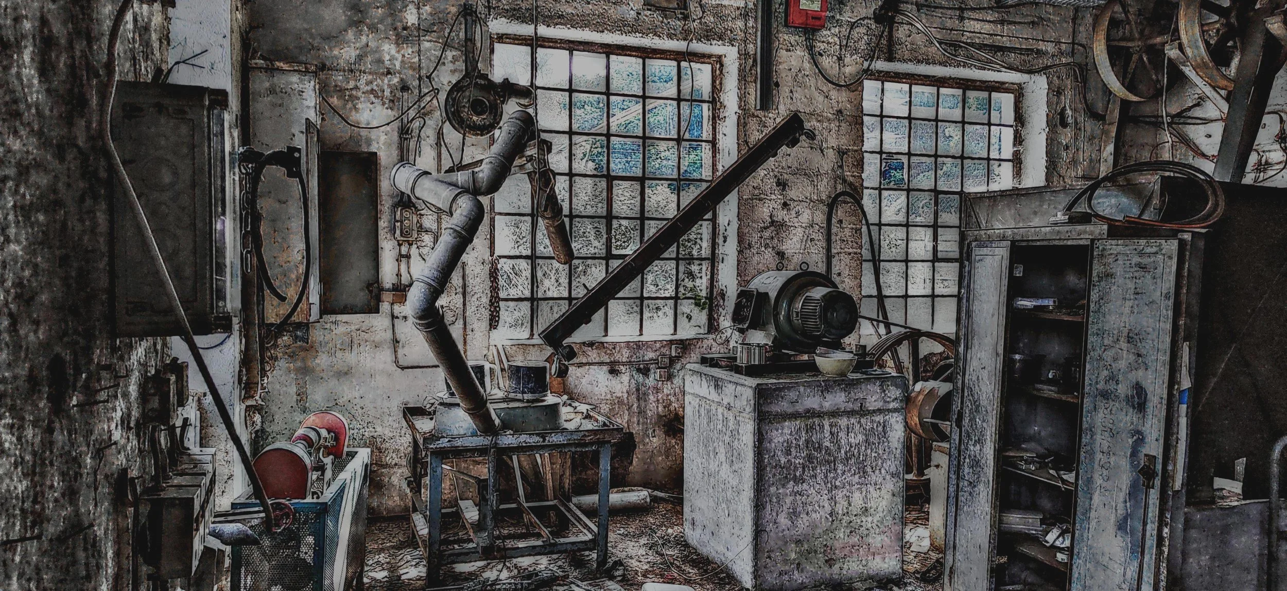 Verlassene, verrostete Werkstatt mit alten Maschinen, Fenstern und Werkzeugen.