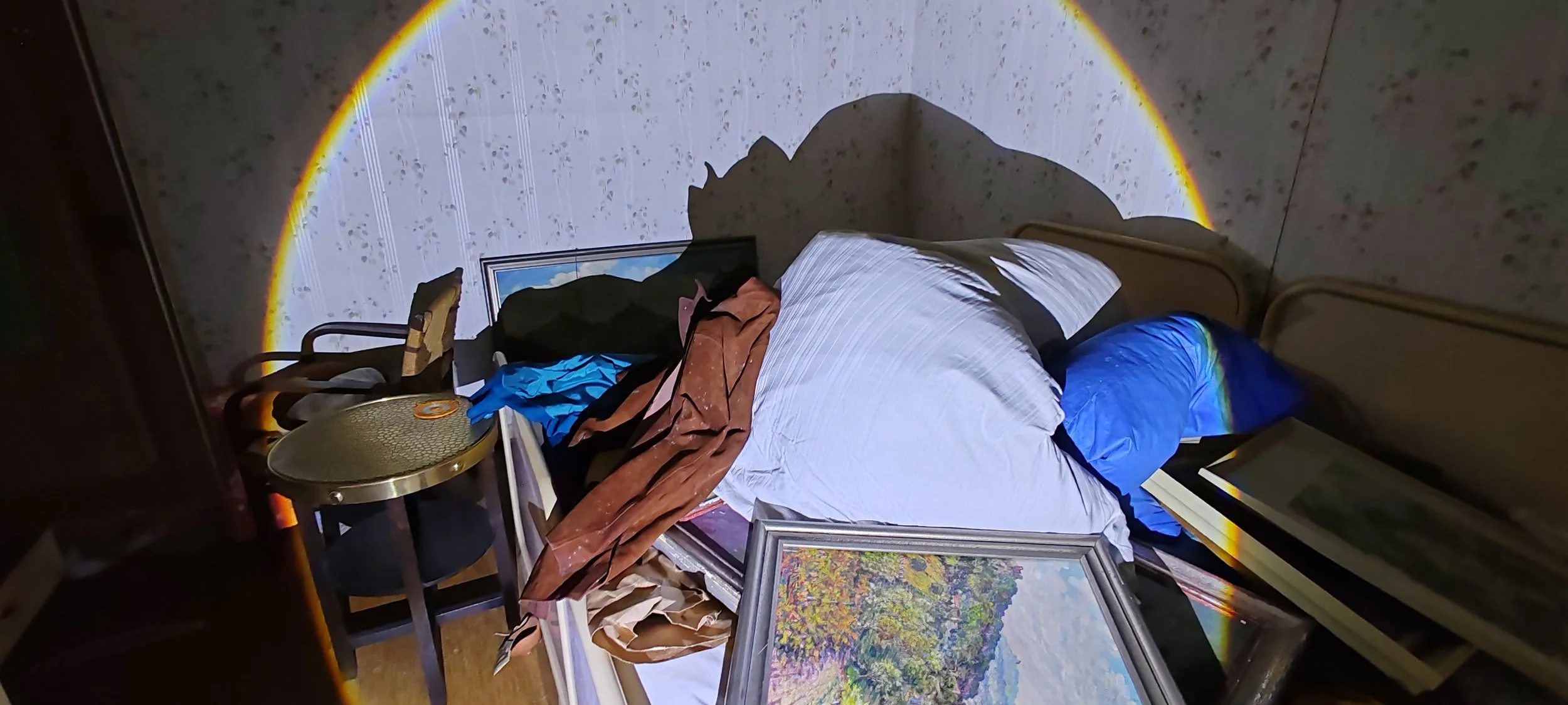 Un ordentlich auf einem Bett liegende Kleidungsstücke und Kunstwerke in einem Zimmer mit Spiegel