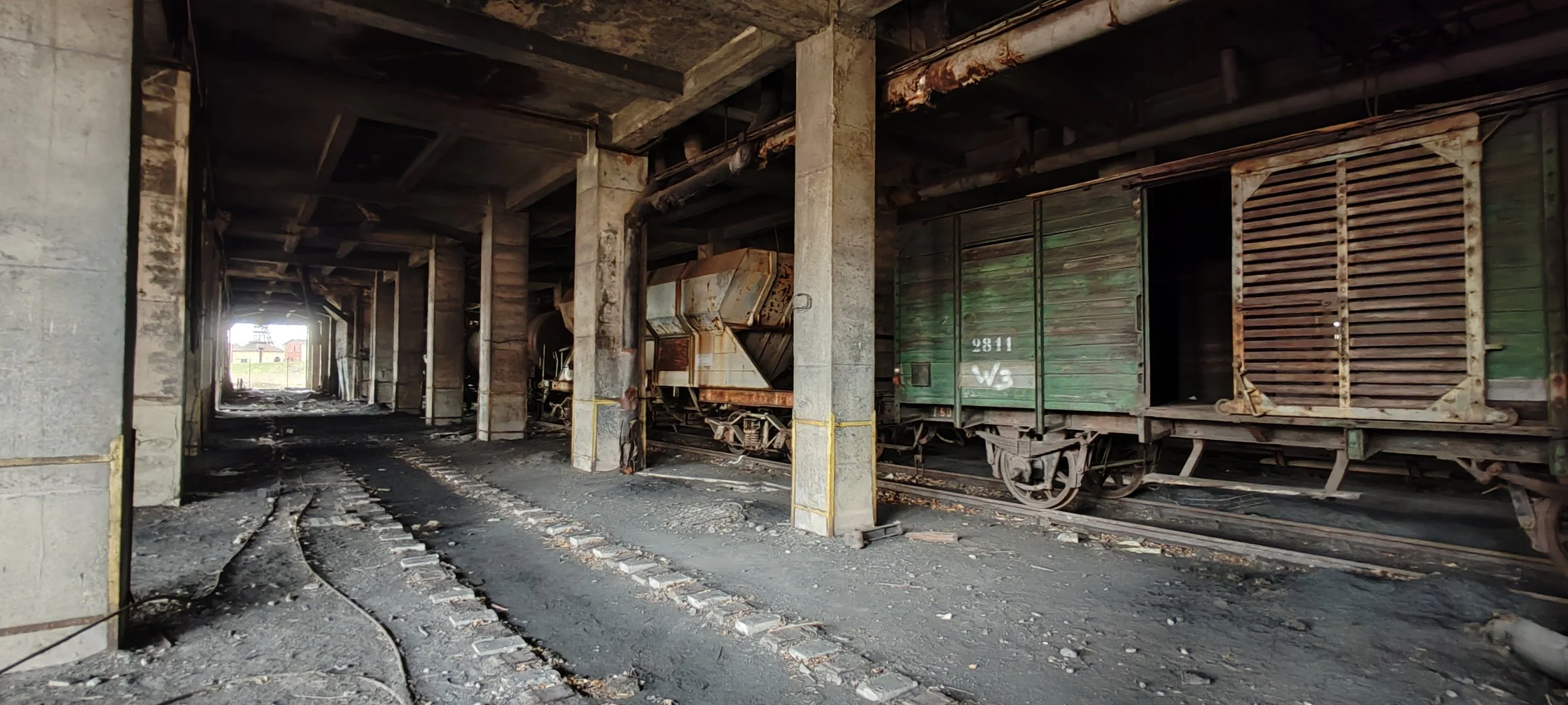 Verlassener, verrosteter Eisenbahnwagen in einem Tunnel. Der Boden ist staubig und ungepflegt.