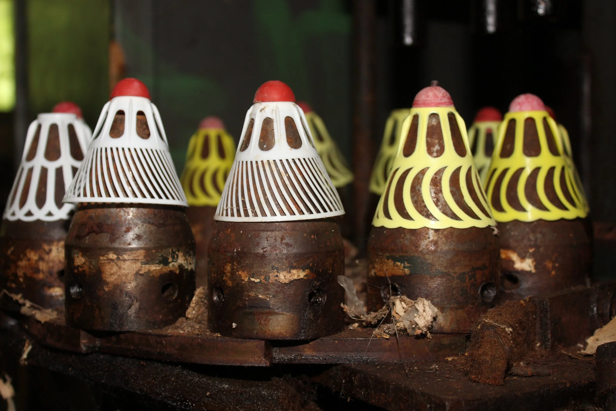 Alterte, rostige Keramik- oder Ziegelstuhlfüße mit bunten Kunststoffkappen in rot, weiß und gelb, auf einem alten Holztisch.