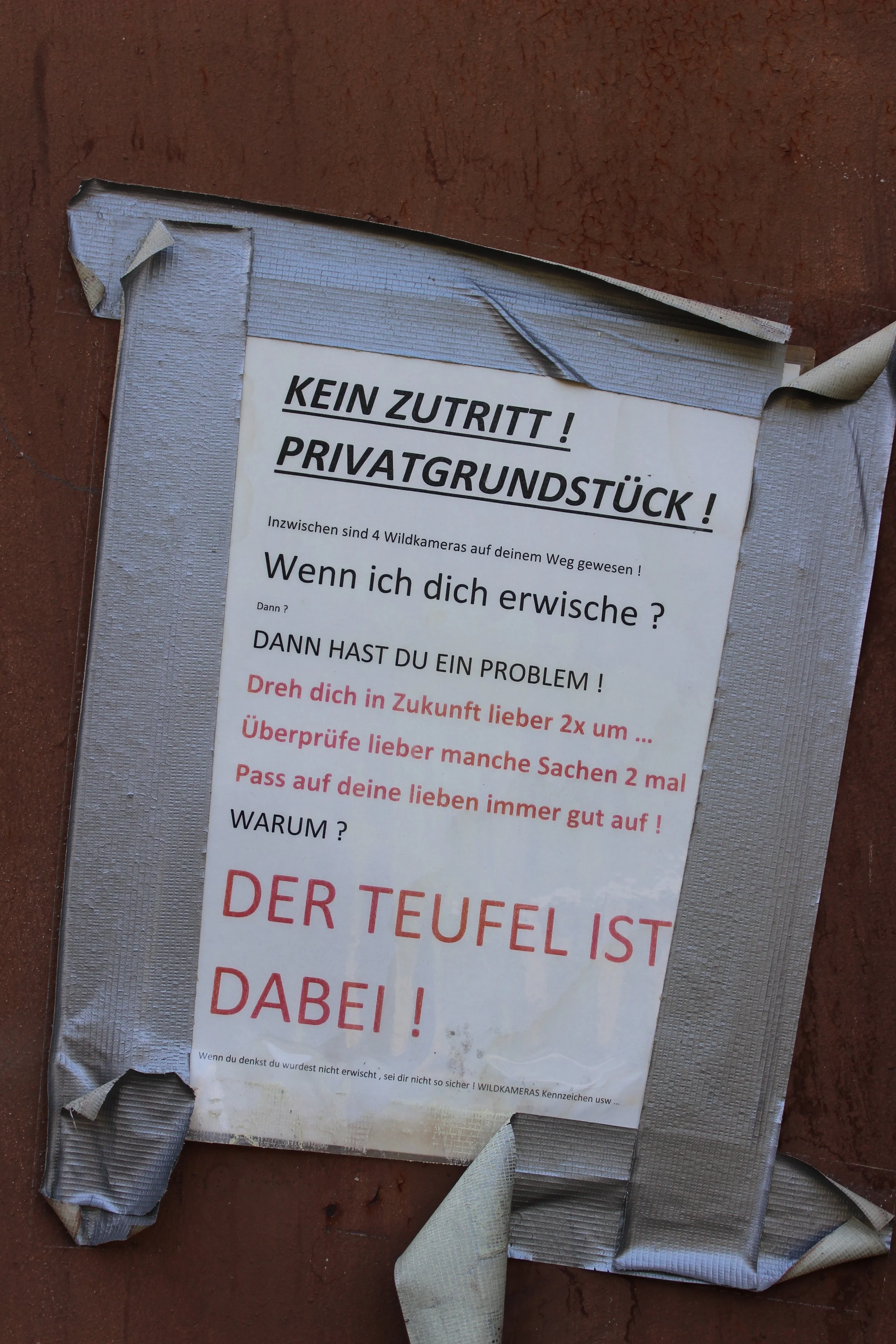 Warnhinweis, dass kein Zutritt zu Privatgrundstück besteht, mit humorvollen Nachrichten über Wildkameras und den Teufel.