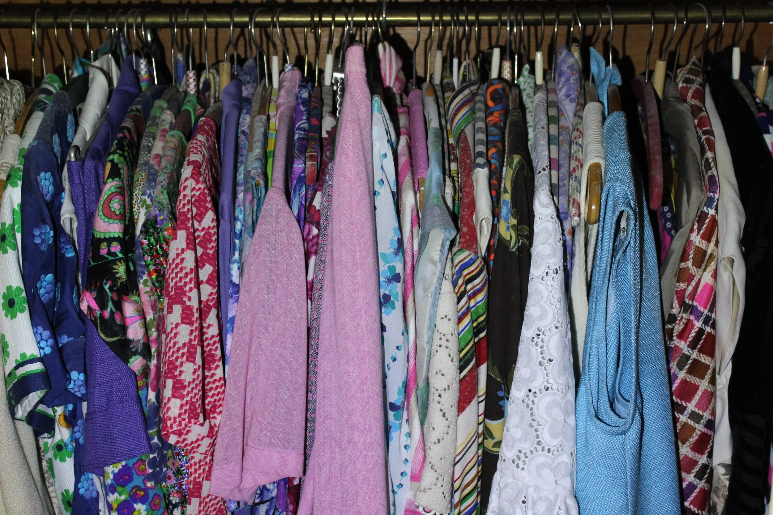 Haufen bunter Hemden und Jacken, die an Kleiderbügeln aufgereiht sind