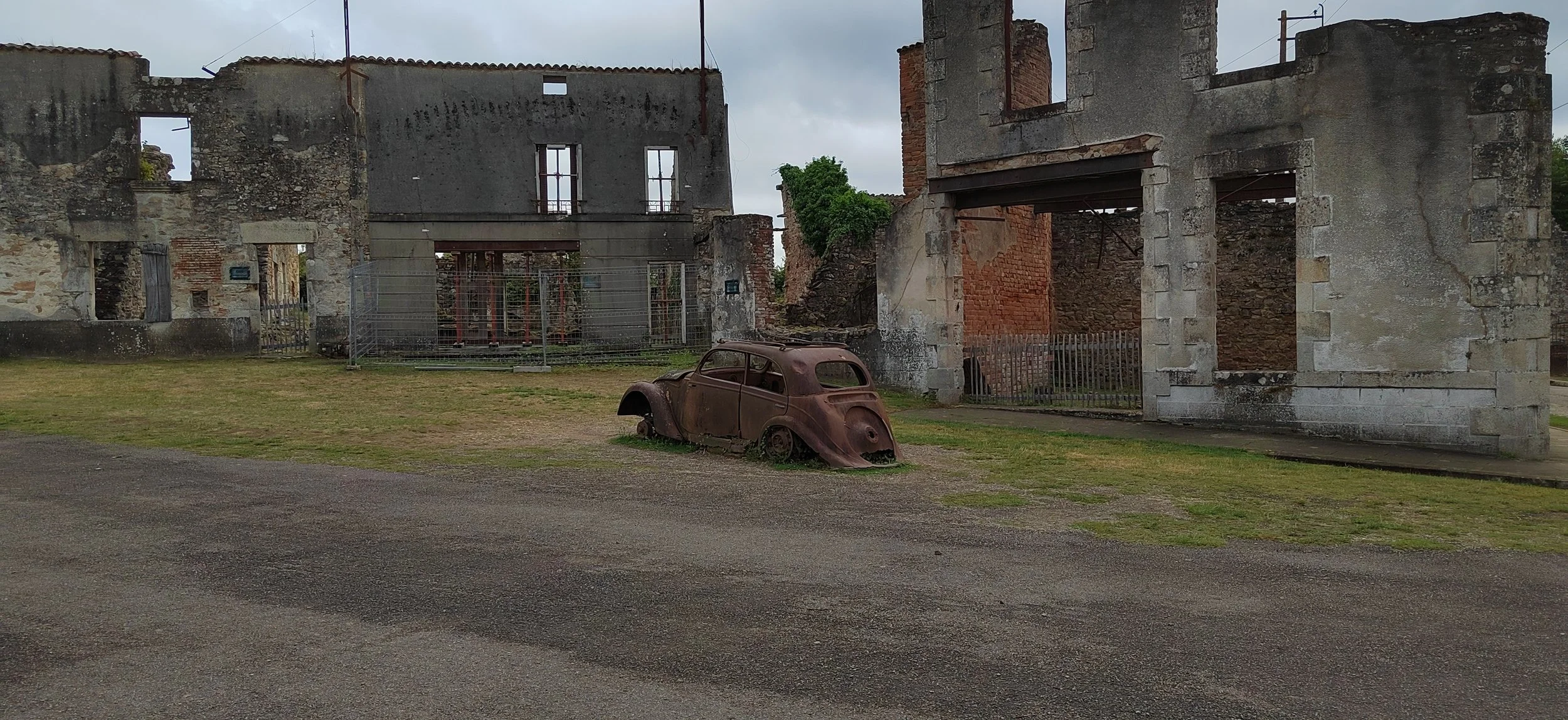 Verfallsene Häuser und ein verrostetes Auto auf einer Wiese