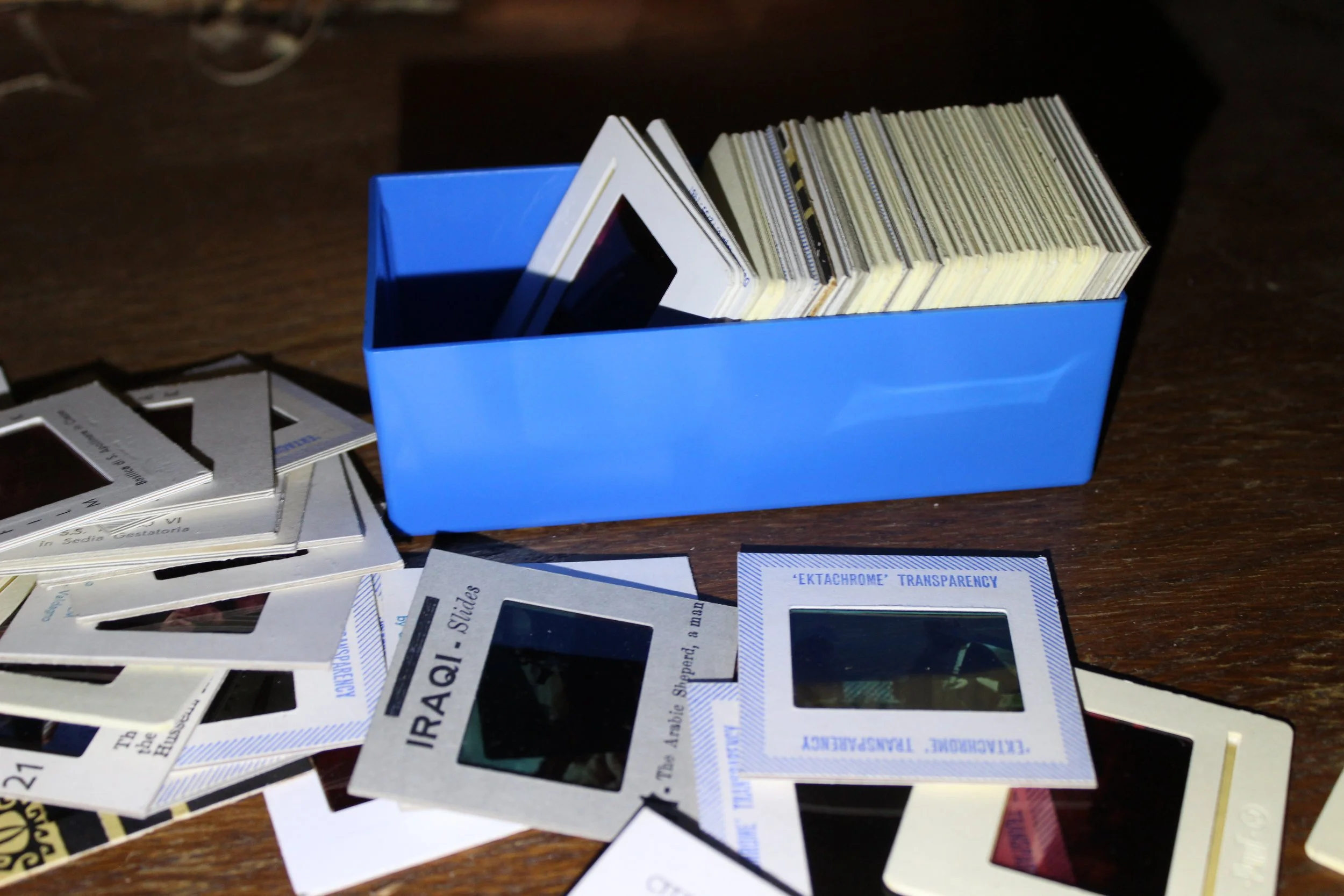 Fotografie von verschiedenen Film- und Negativeinrahmungen auf einem Holz-Objekt, mit einer blauen Box, die eine Sammlung von Filmen enthält.