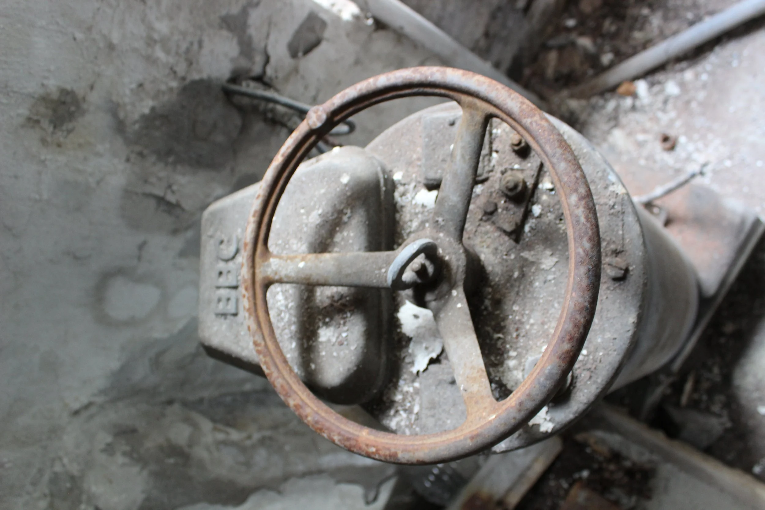 Altrohrventil mit rostigen Griff, auf einer verschmutzten Oberfläche.