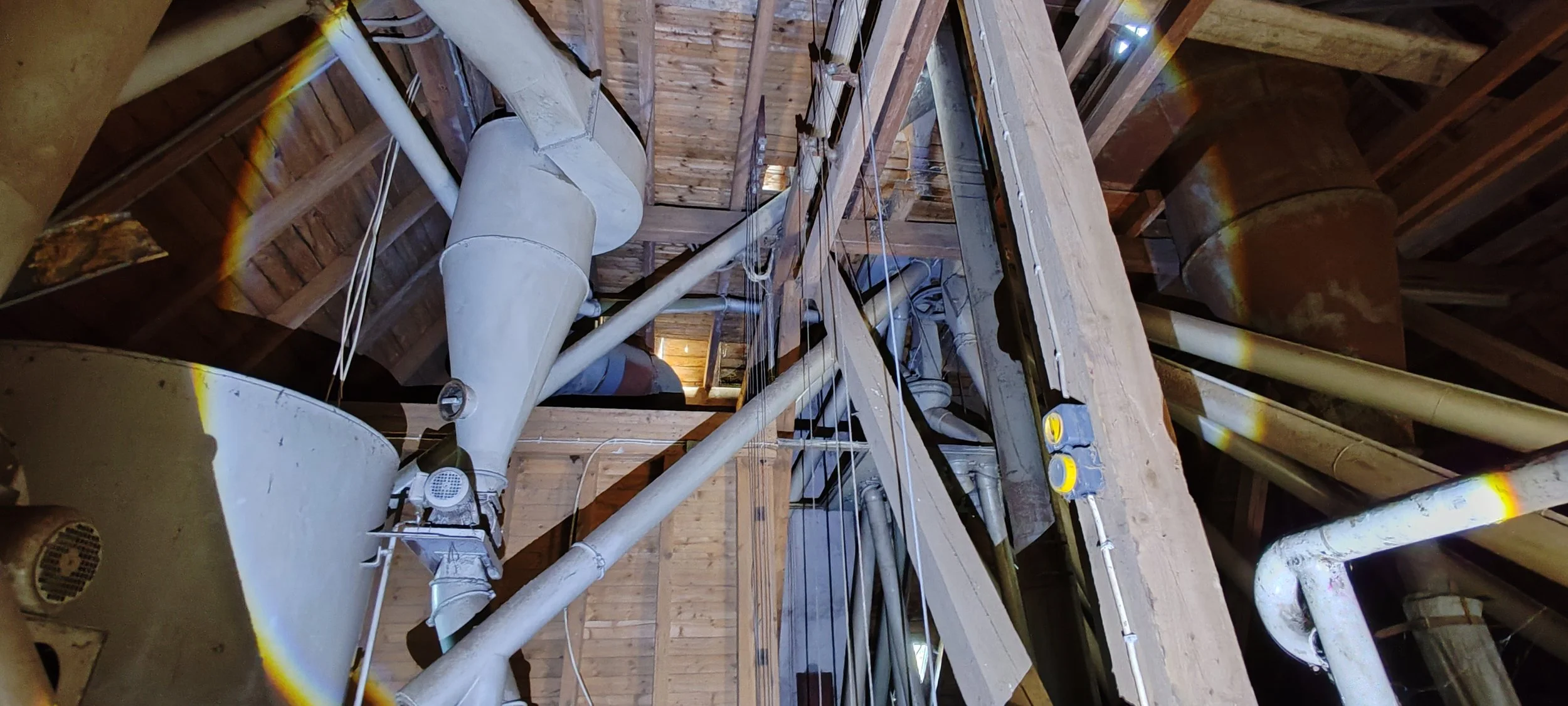 Innenaufnahme eines industriellen Kessels oder Ofens mit Rohren und Schweißnähten, sichtbar in einer Holzunterkonstruktion.