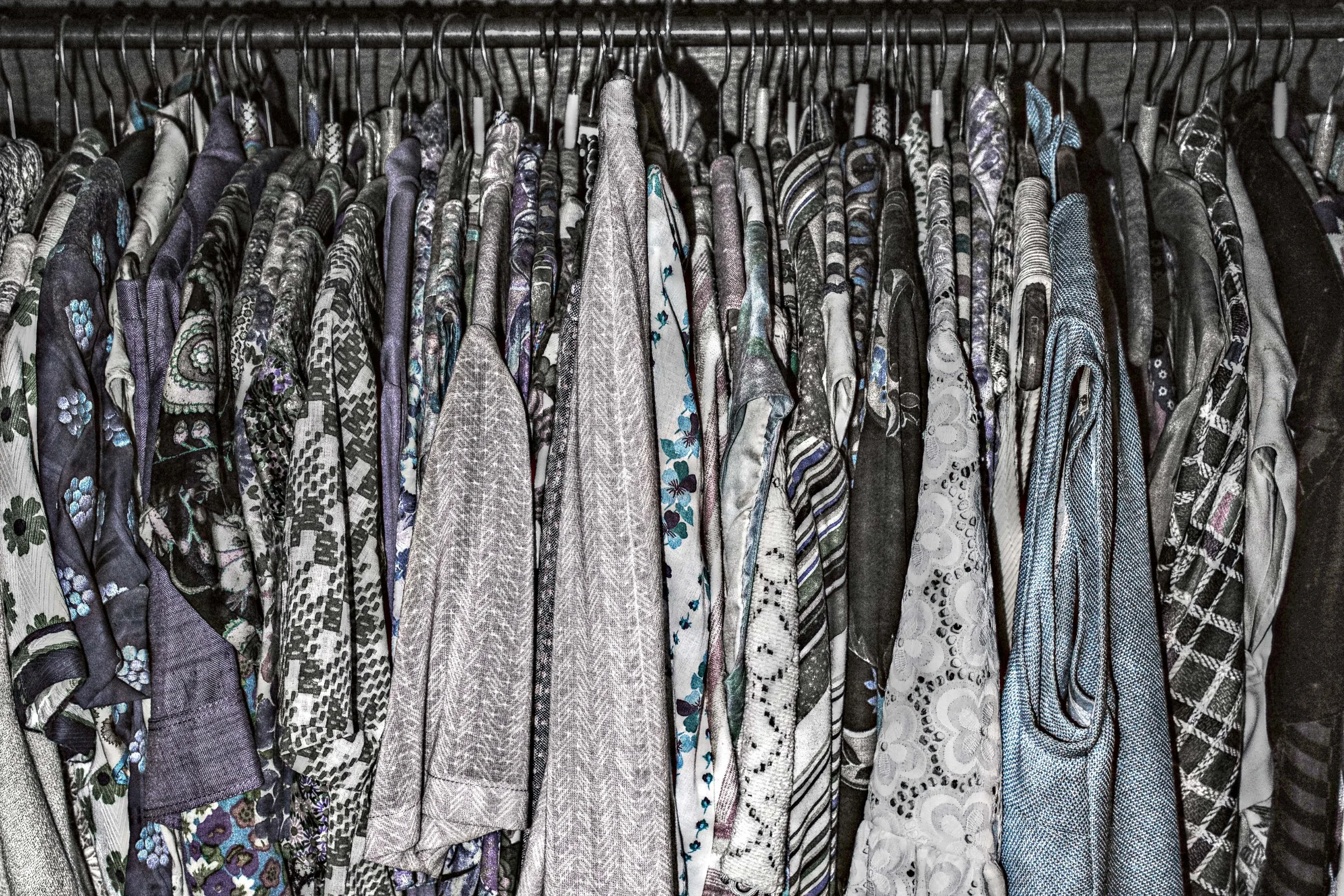 Häufig getragene Hemden auf Kleiderstange in einem Kleiderschrank, viele mit Blumenmustern und in neutralen Farben