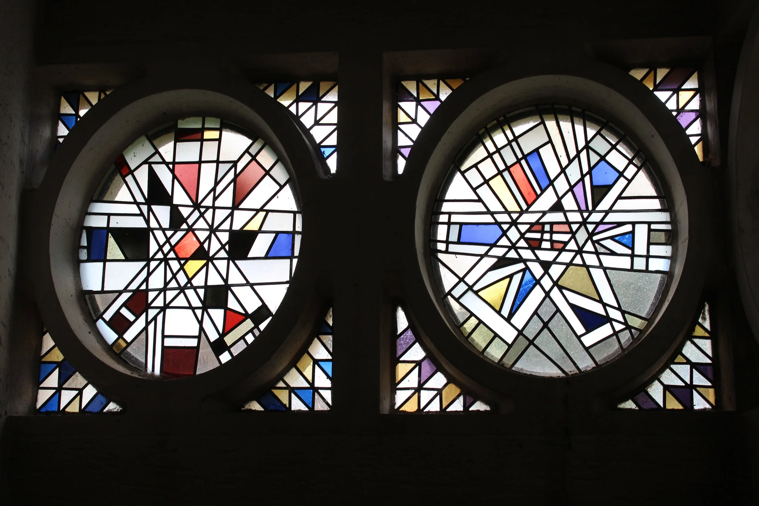 Bunte Buntglasfenster mit geometrischen Mustern in einer Kirche