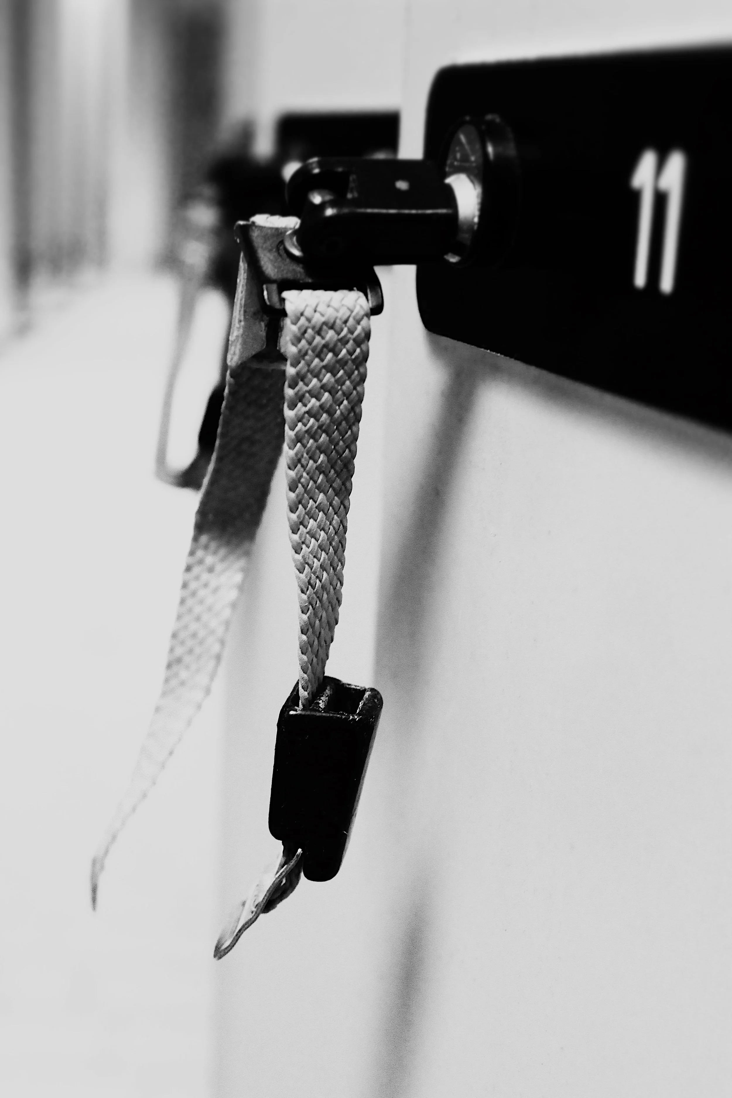 Ein schwarzer Schlüsselbund hängt an einer Hakenleiste mit der Nummer 11 in einer Umgebung, möglicherweise im Büro.