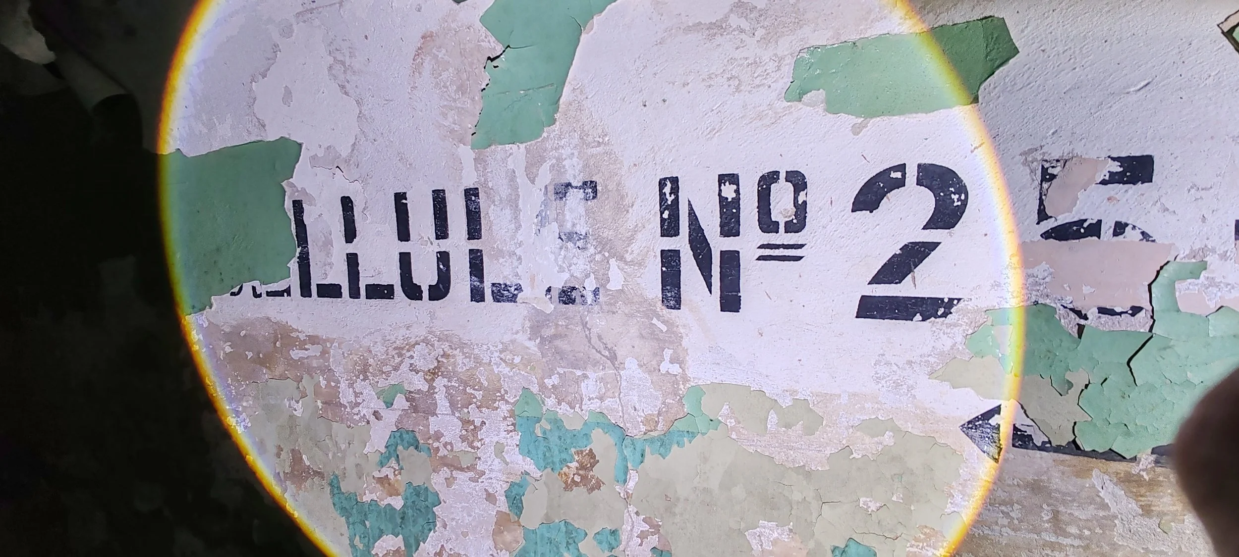 Verblasste und abblätternde Wandfarbe mit verblasster Aufschrift 'SOUTH 2'.