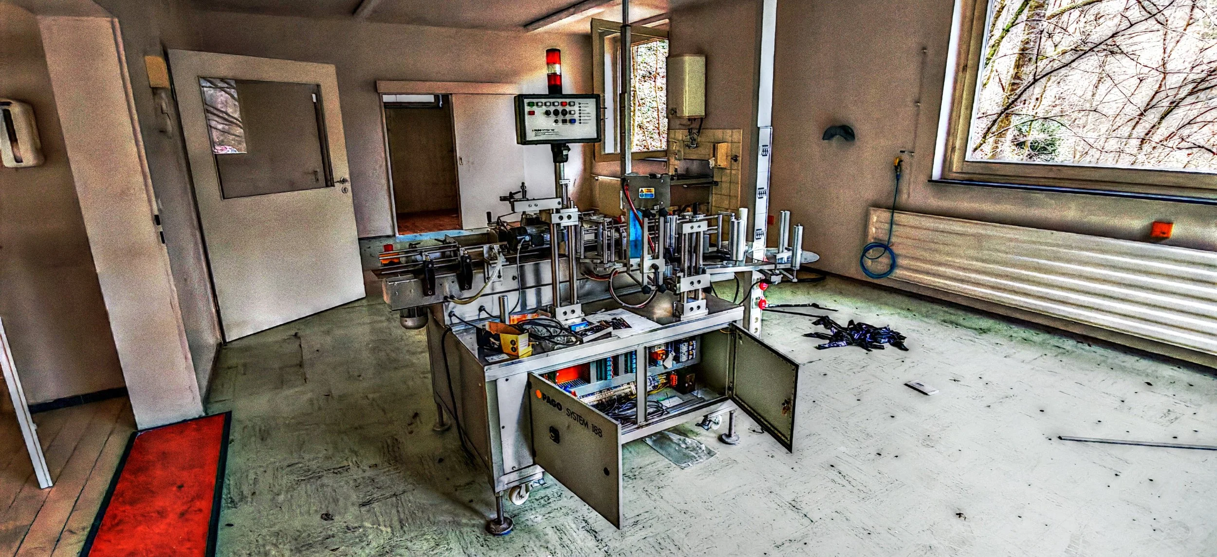 Ein Arbeitsraum mit technischen Geräten, einem Fenster und einem offenen Kabinett im Vordergrund.