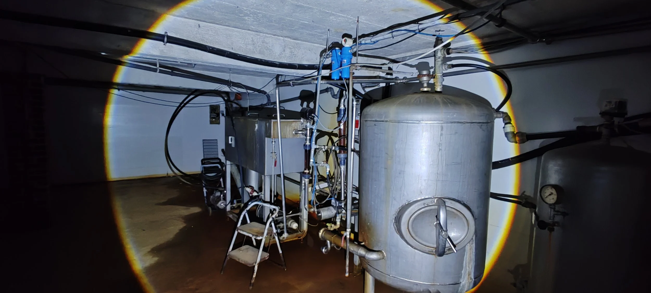 Maschinen und Tanks in einem dunklen Raum, beleuchtet durch einen Lichtkreiseffekt