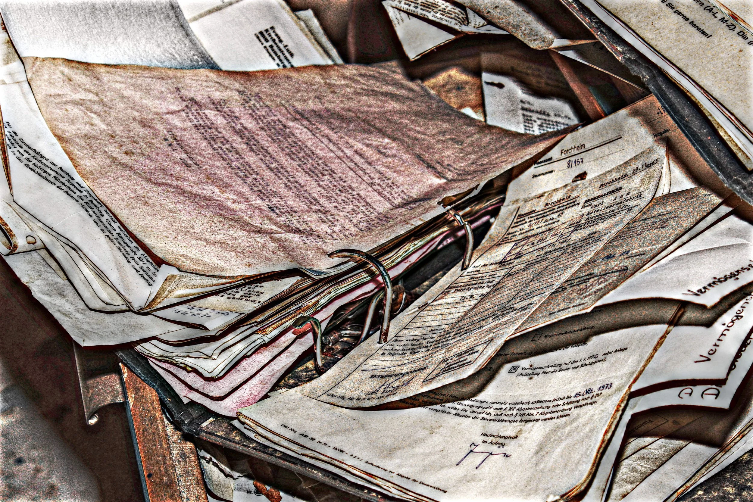 Ein Stapel alter, zerknitterter Dokumente und Papiere, teilweise in Ordnern abgeheftet, in einem Ablagefach.