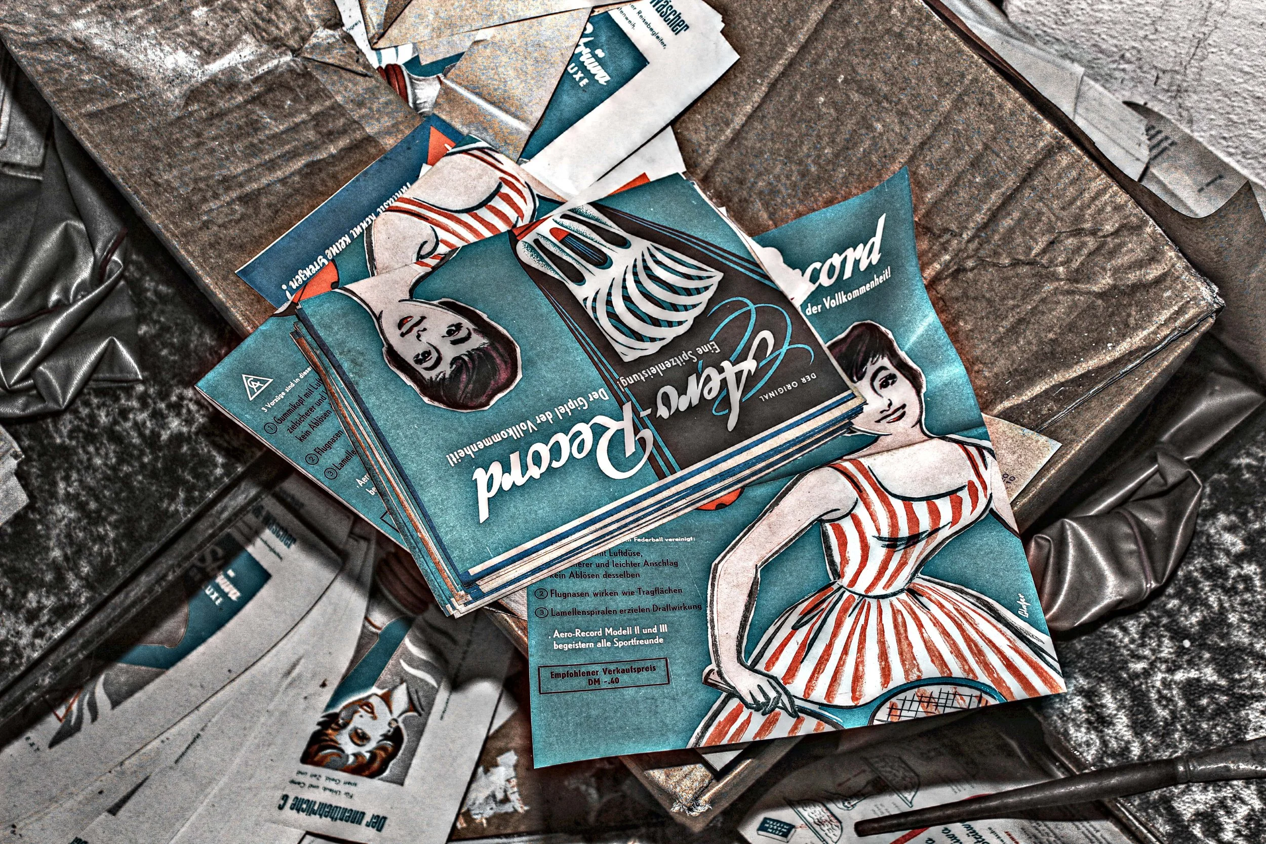 Zufällige Werbung für einen Retro-Style Tennis-Schläger mit einer stilisierten Frau in einem rot-weißen Streifen-Kleid, die einen Tennisschläger hält, auf einer alten, staubigen Oberfläche in einer verfallenen Umgebung.