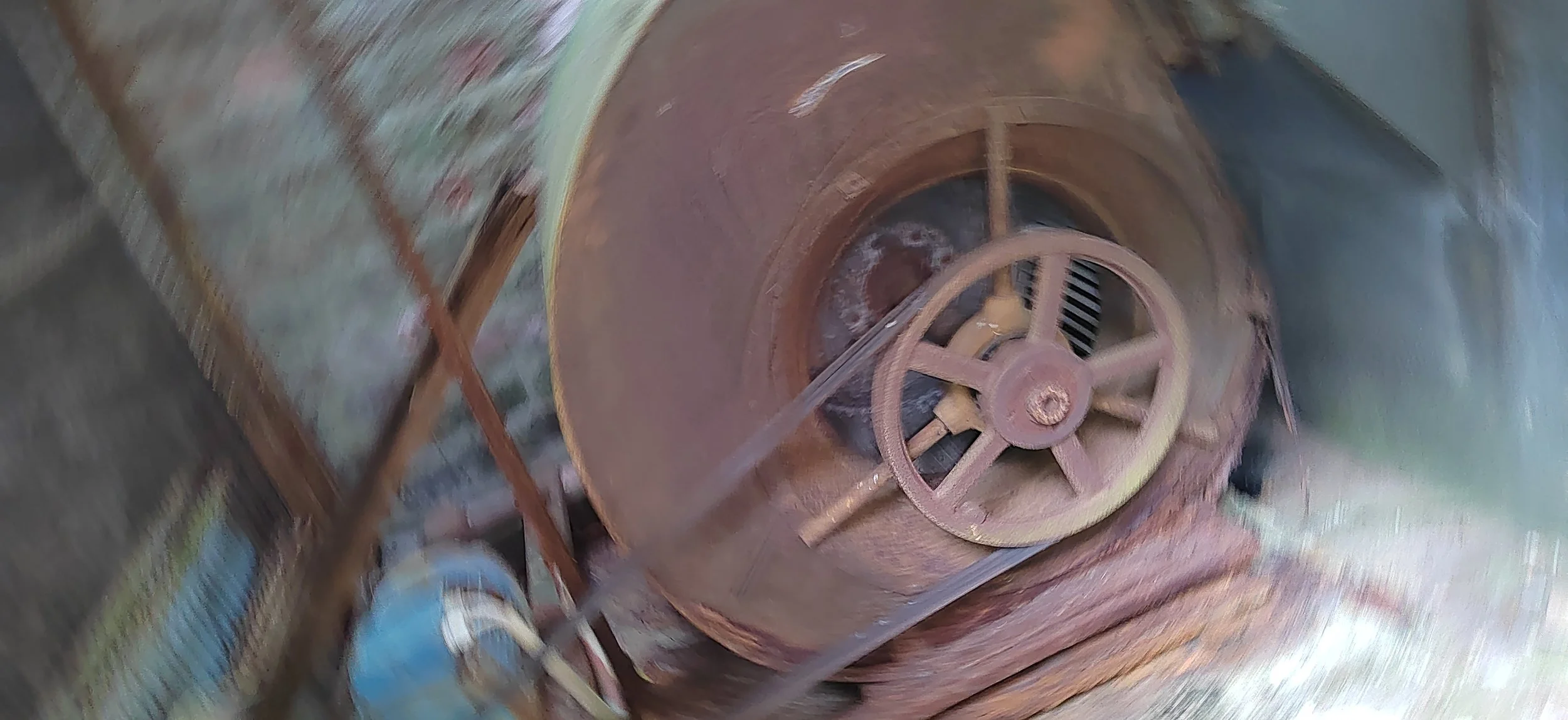 Alte, rostige industrielle Maschine mit großen Rädern und Getriebe, in einem rustikalen Umfeld