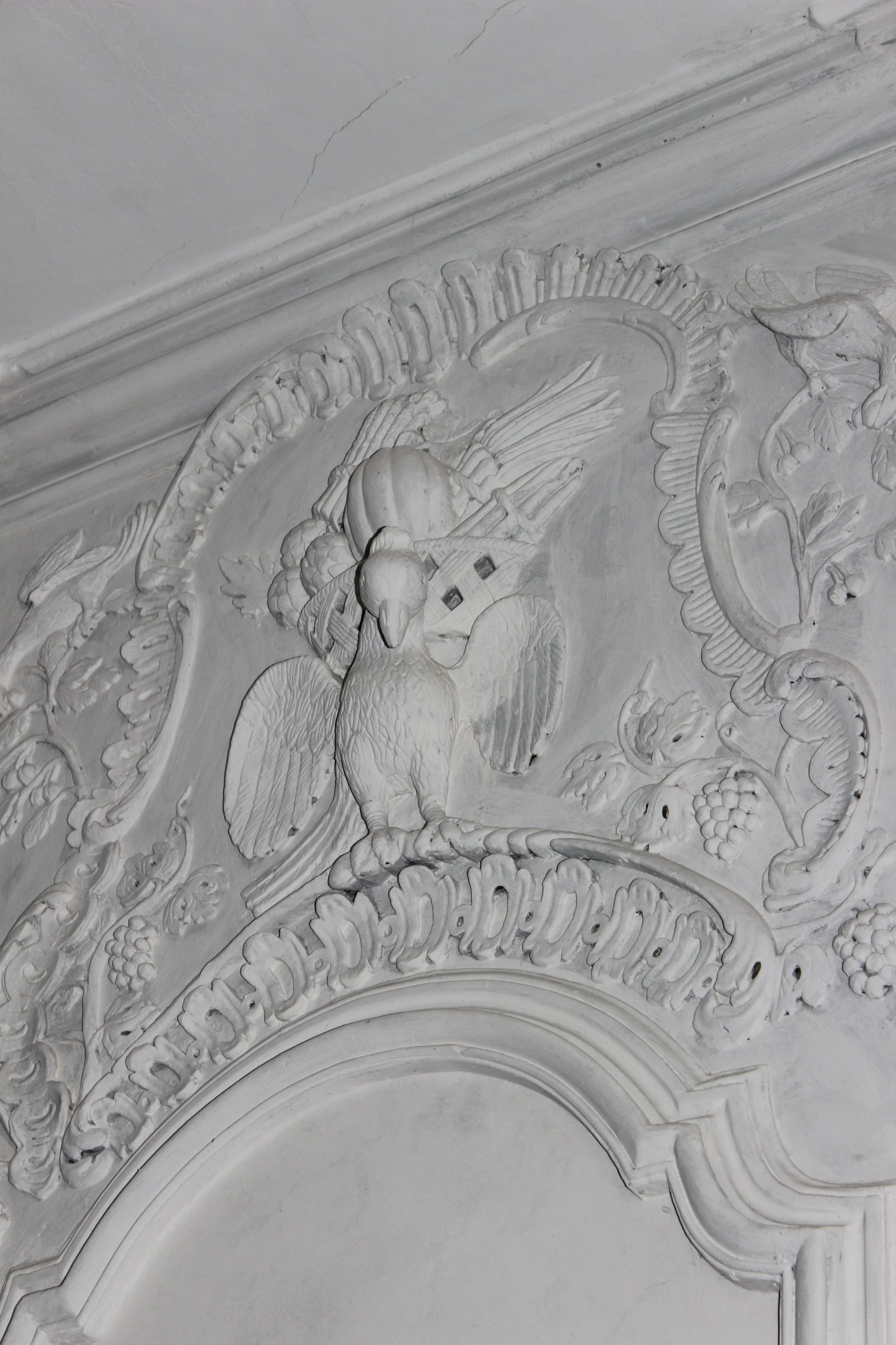 Barocke Stuckdekoration mit einem Adler, Bäumen und Schriftband auf einer weißen Wand