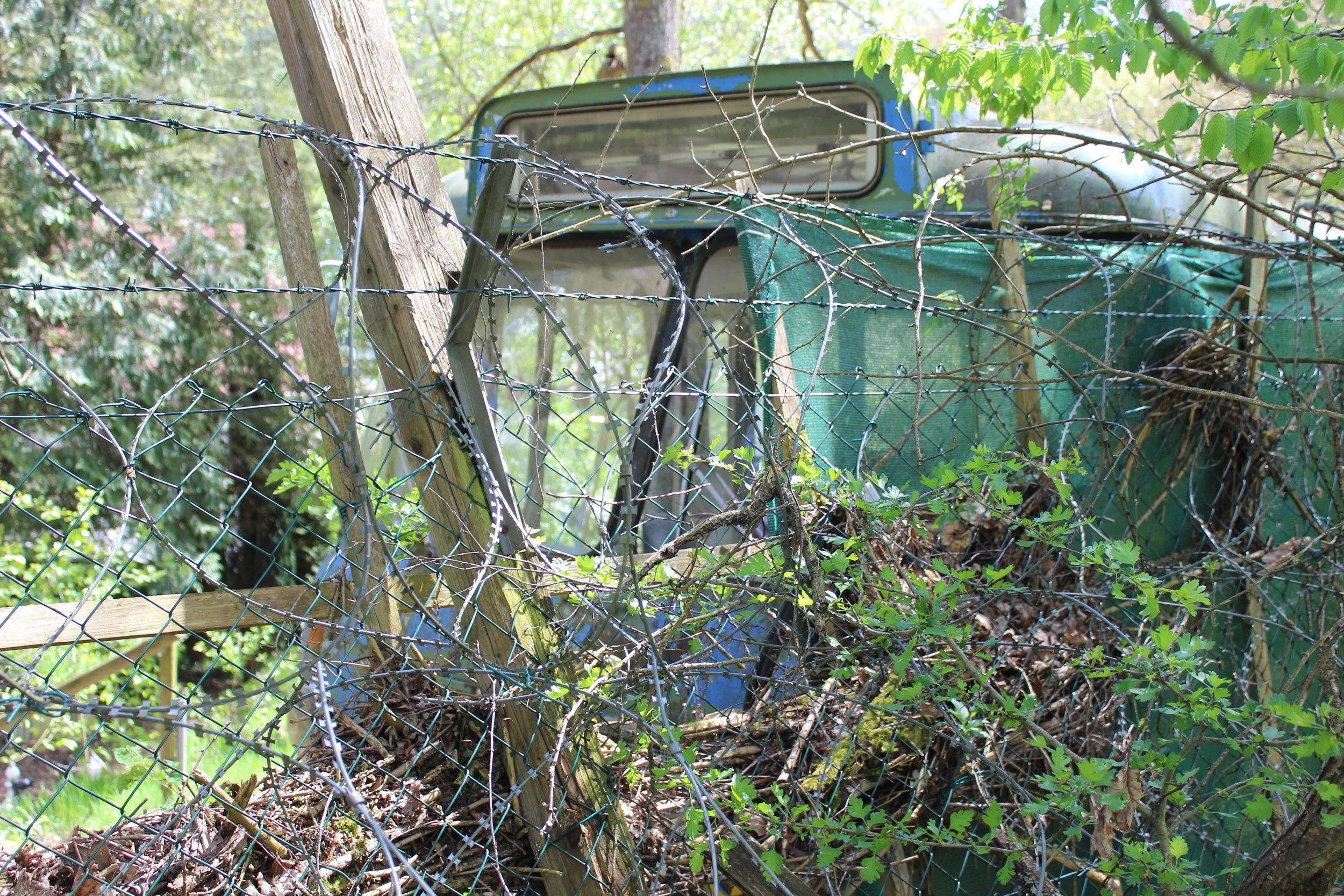 Verrosteter, alter Traktor, umgeben von Stacheldraht, im Grünen close-up