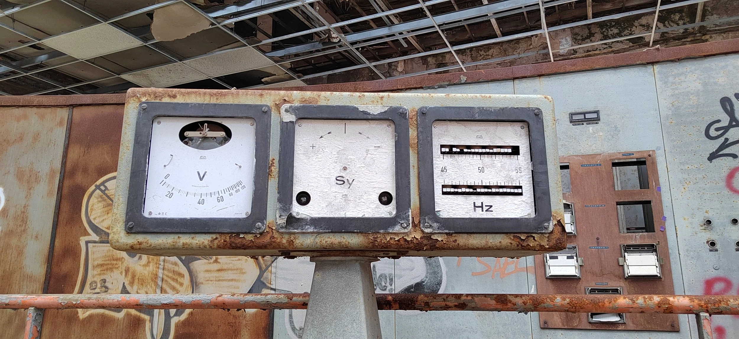 Altes, rostiges Messgerät mit Voltmeter, Schraubendreher, und Frequenzmesser, in einem verlassenen Ort mit Graffiti