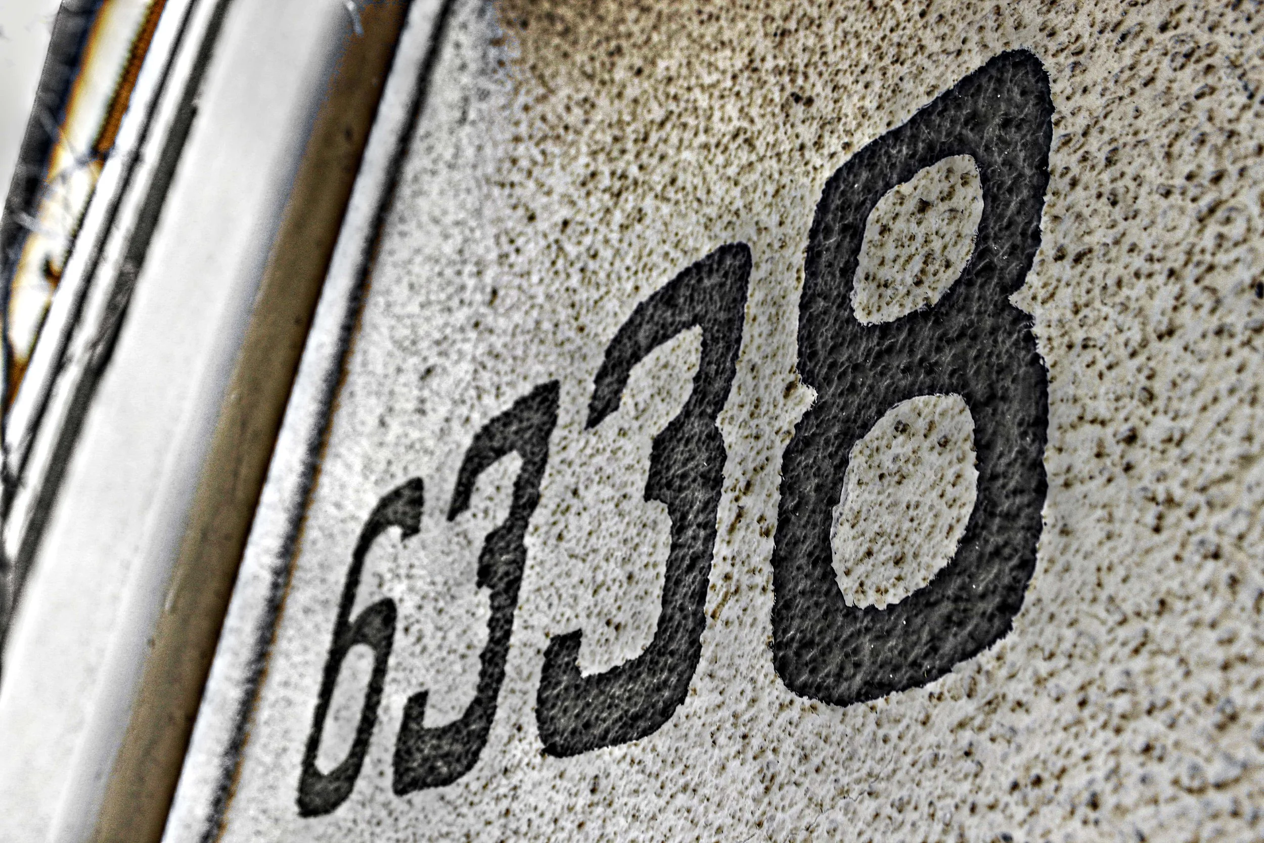 Straßenschild mit der Zahl 60 in schwarz auf einer hellen, rauen Wand