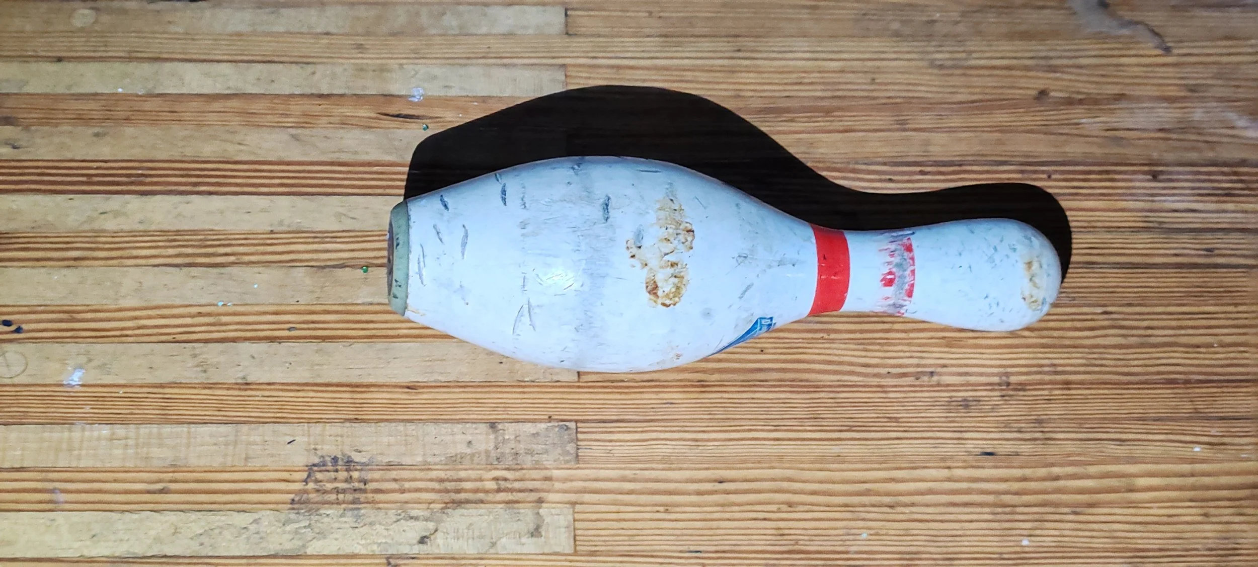 Ein alter, zernarbter und verschmutzter Flaschensammler, der wie eine Bowlingkugel aussieht, liegt auf einem Holztisch.