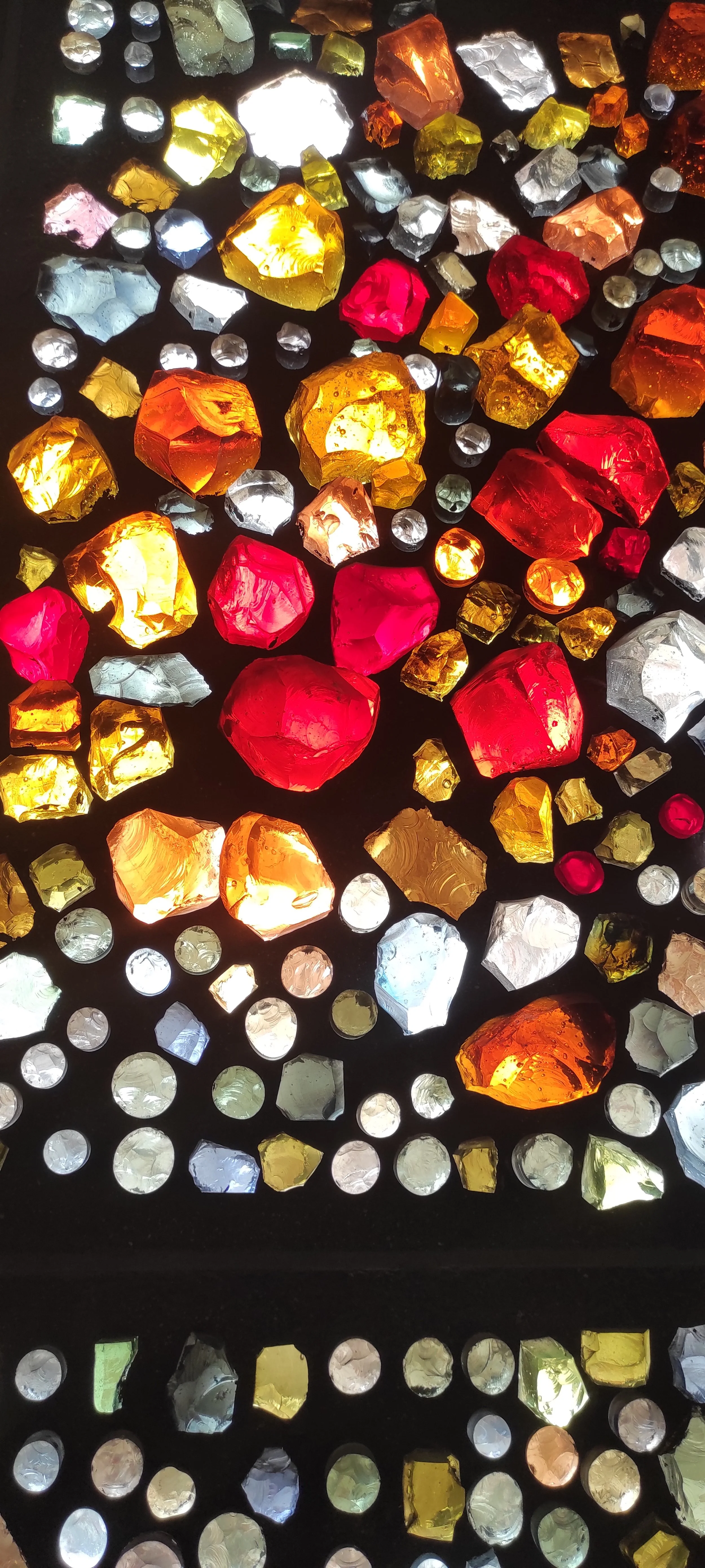 Bunte Edelsteine in verschiedenen Farben, die auf einer dunklen Oberfläche liegen.