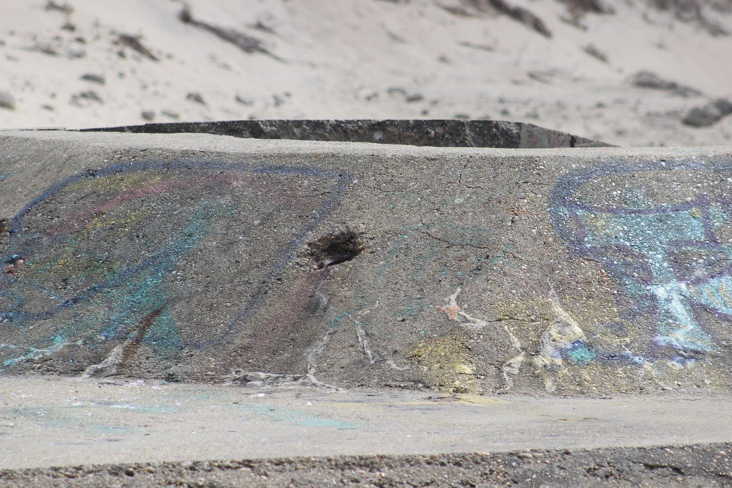 Graffiti auf einer Betonmauer in einer Wüstenlandschaft.