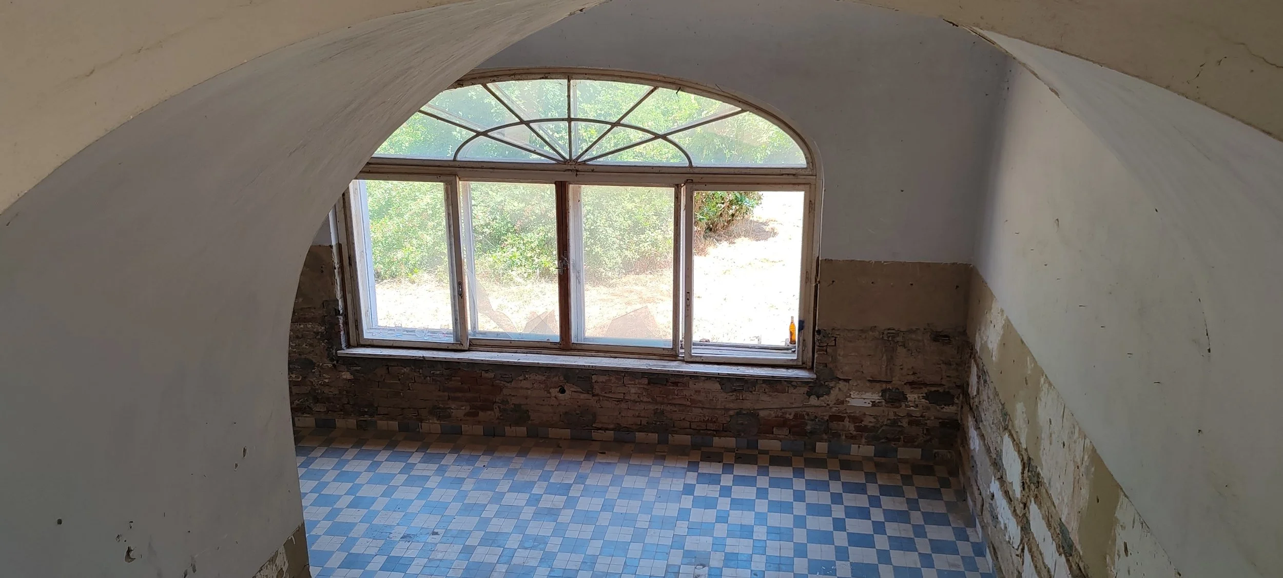 Ansicht eines renovierten Raumes mit einem großen Fenster, unvollständige Wände und einen bunten Fliesenboden.