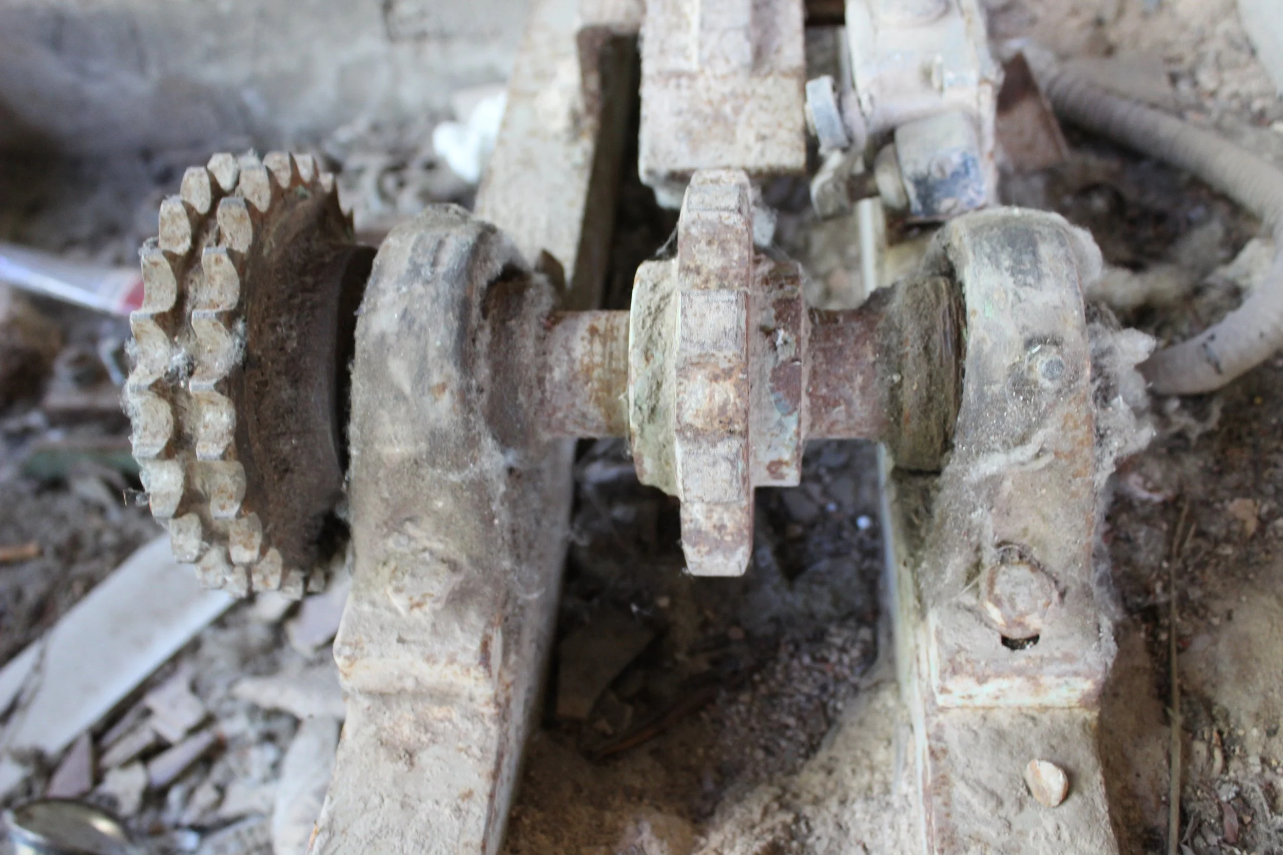 Alte, verschmutzte Metallteile und Zahnrad in einer Baustelle oder Werkstatt.
