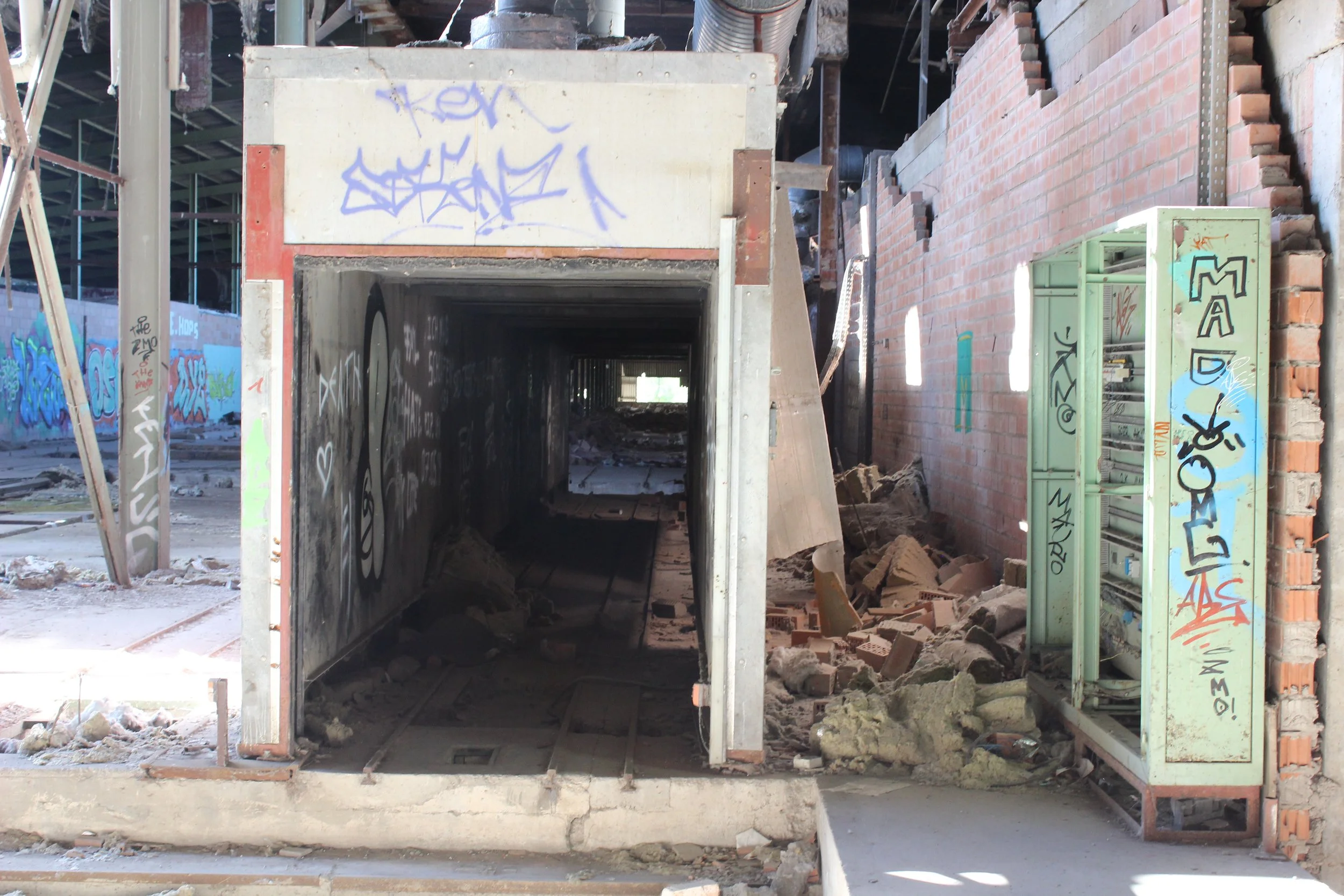 Verfallene graue und grüne Boxen, zersplitterte Wand und Graffiti, Trümmer und Schutt auf dem Boden in einem verfallenen Gebäude