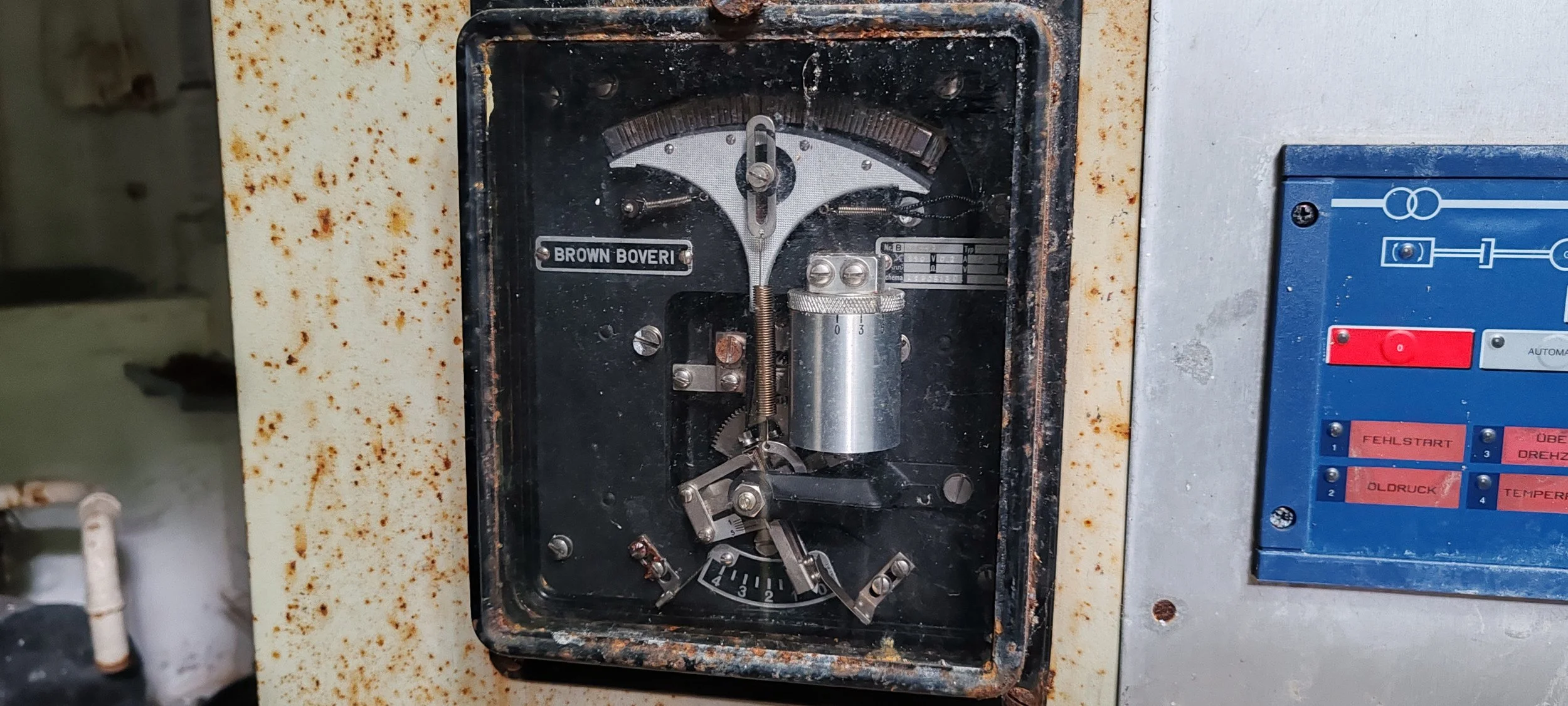 Altertes Messgerät mit der Aufschrift 'BROWN BOVERI', showcasing ein Zeigerinstrument, ein Drehregler und verschiedene Skalen, in einem alten industriellen Umfeld.