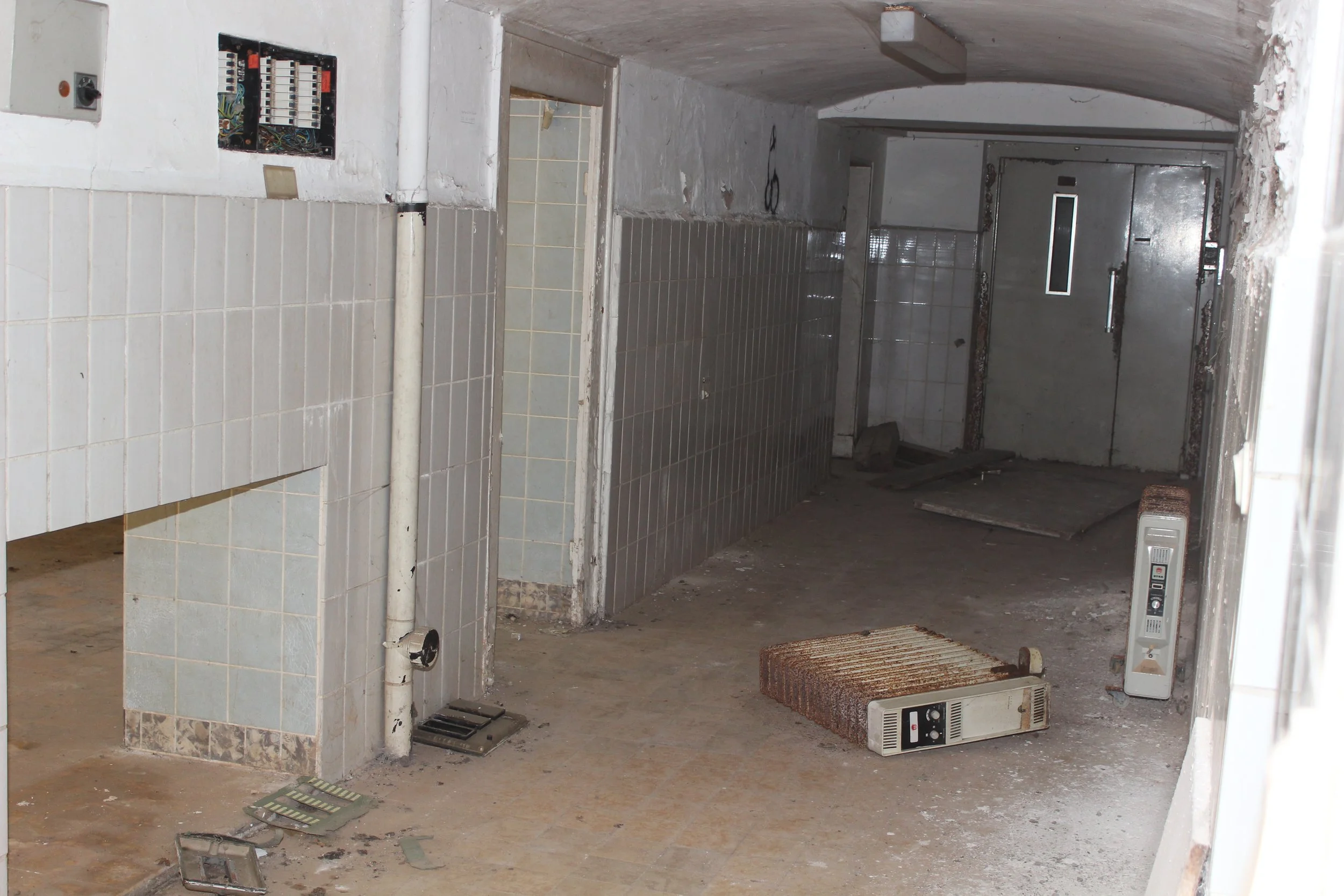 Verlassenes, schmutziges und beschädigtes Gebäude mit kaputten Heizkörpern und verlegten Kabeln.