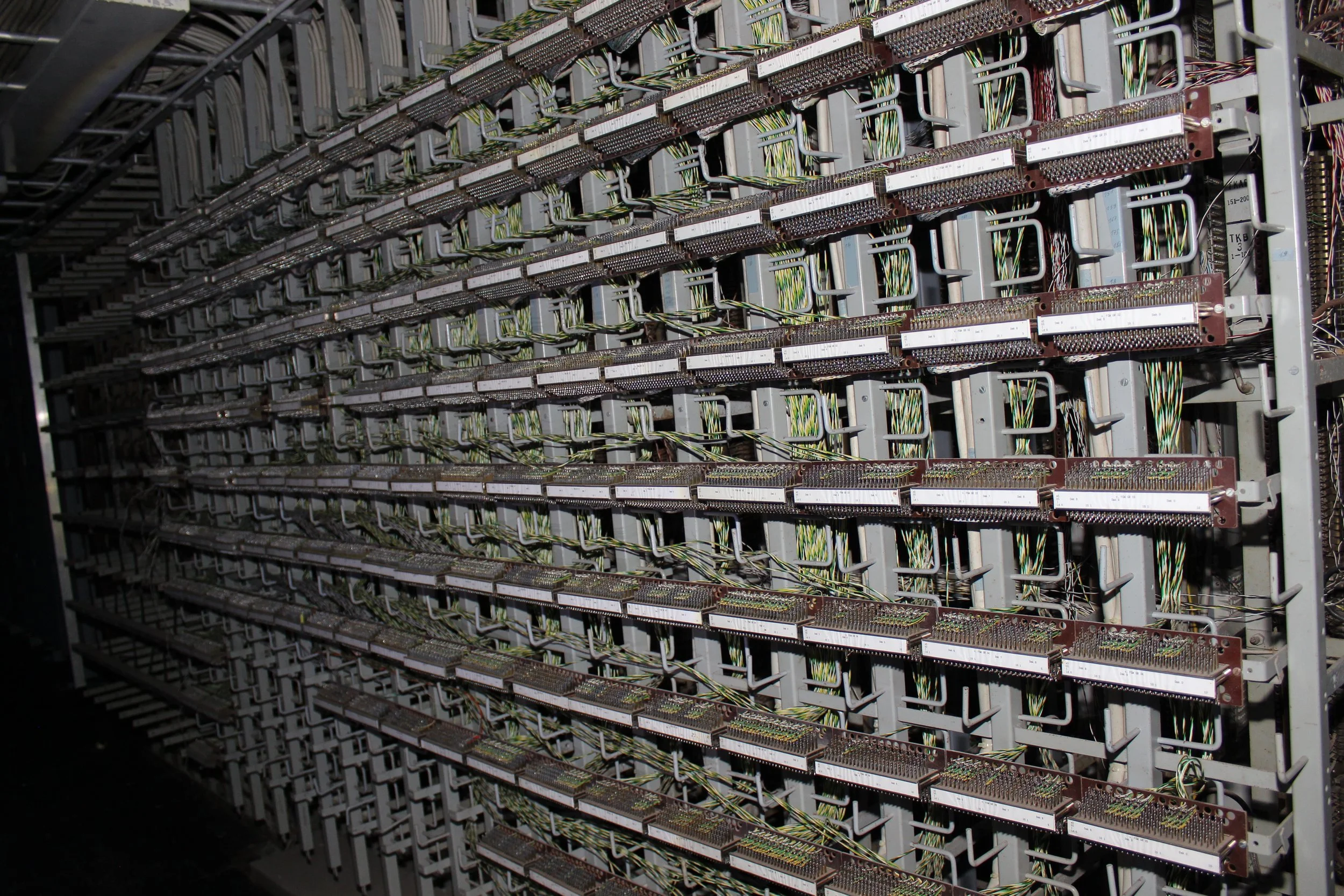 Ein Blick auf eine große Server- oder Rechenzentrale mit mehreren horizontalen Reihen von ausgestatteten Komponenten, verbunden durch Kabel.