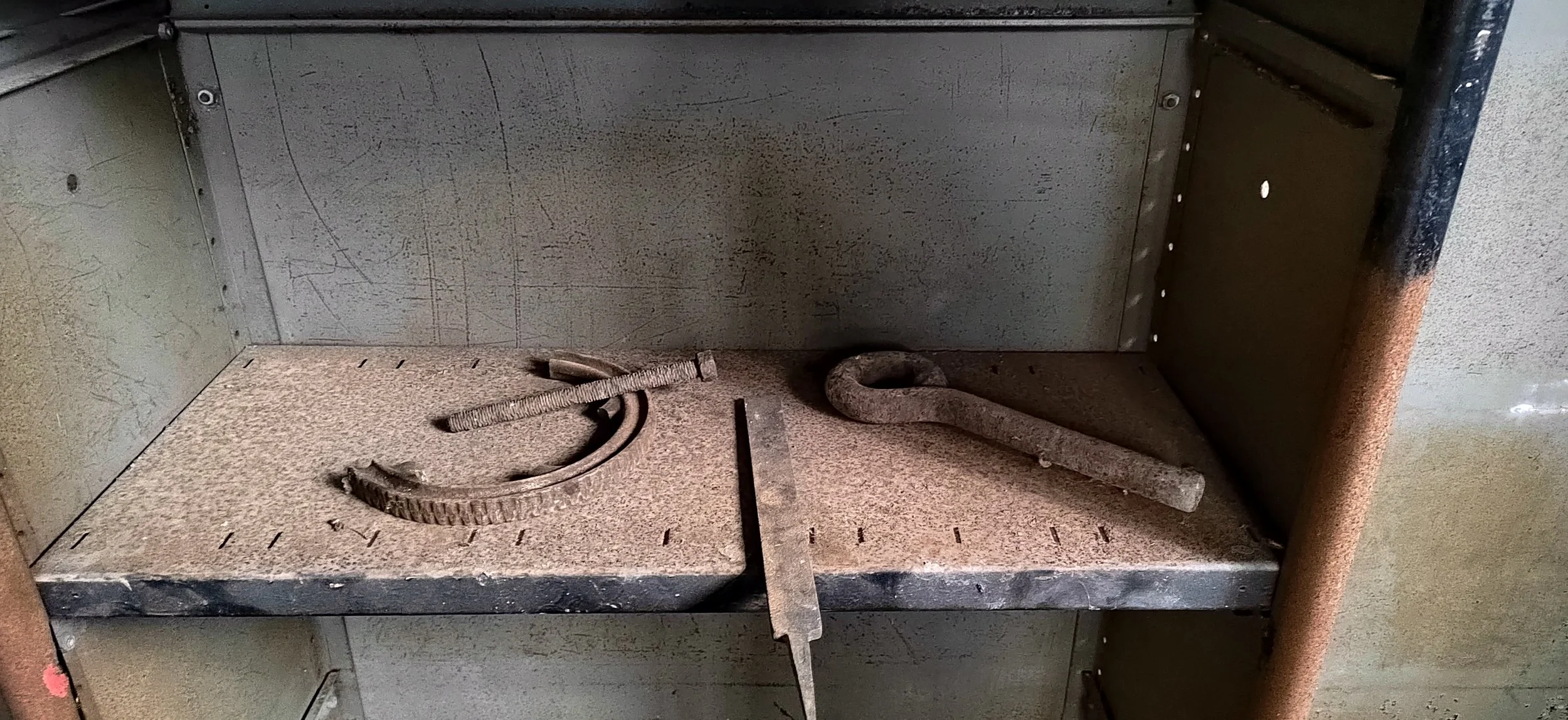 Alte, rostige Werkzeuge und Werkstattgegenstände auf einer Metallablage, möglicherweise in einer Werkstatt oder Garage.